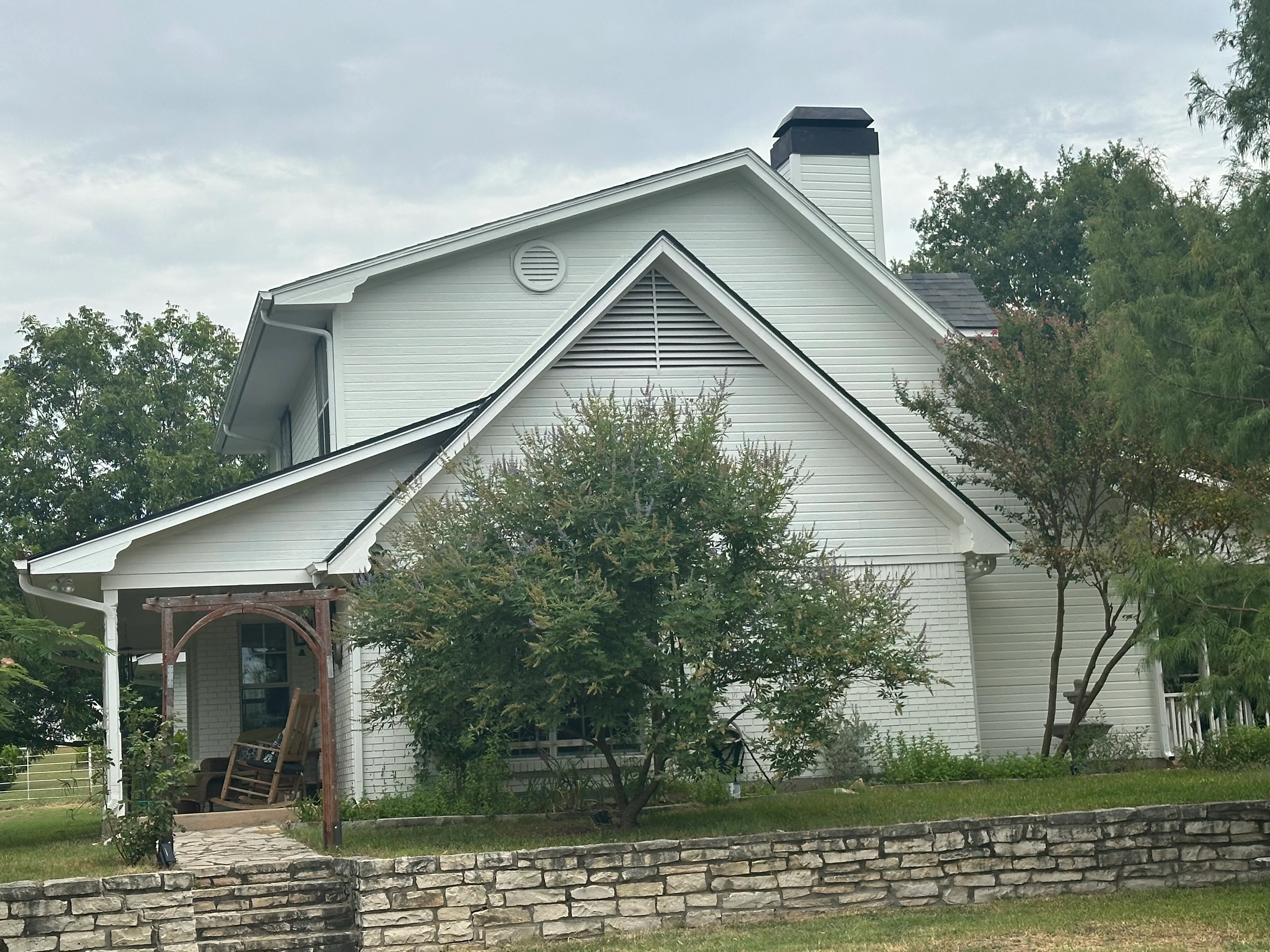 Two-story home with new dark shingle roof, white fascia, and brick chimney with cap