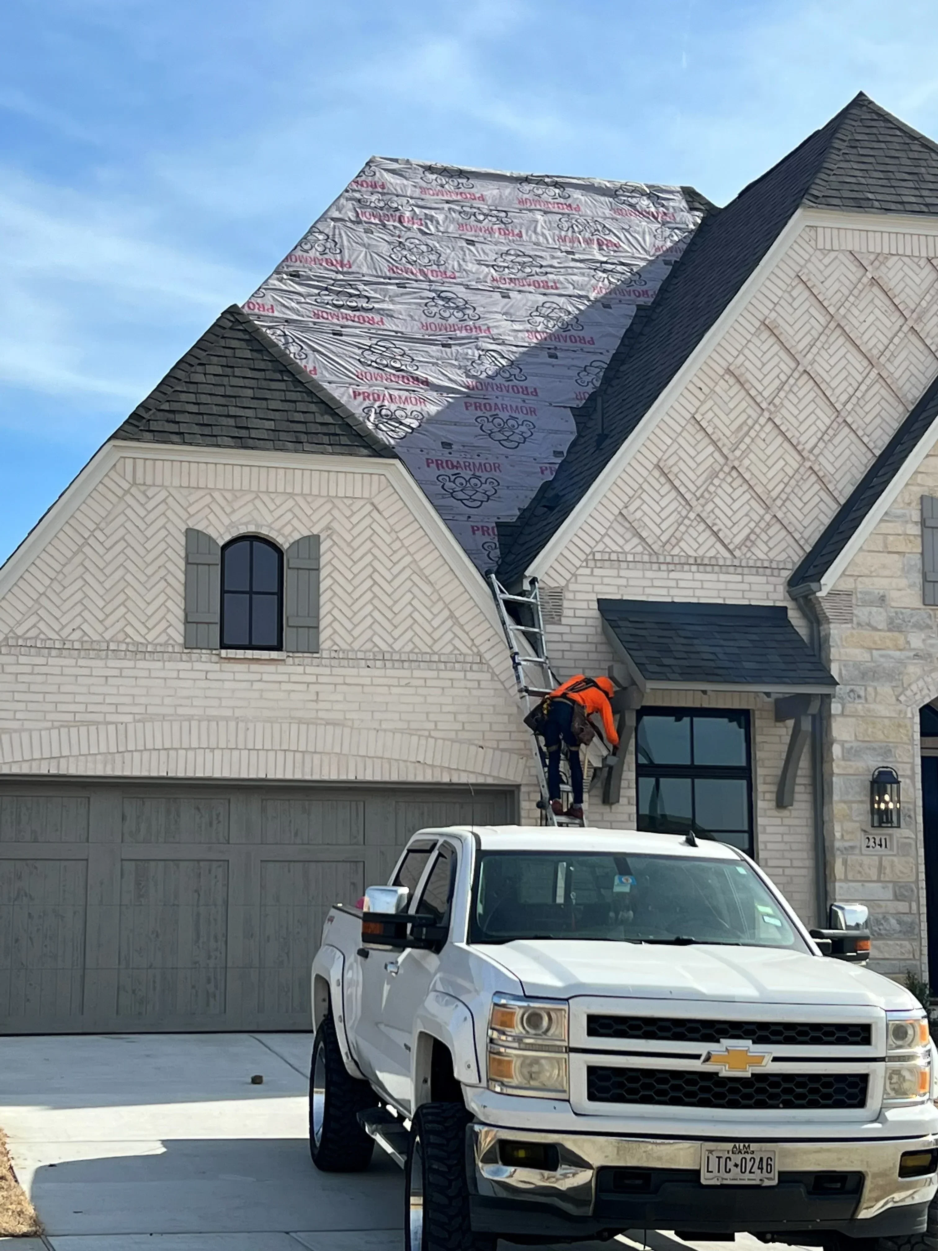 Herringbone shingle roof installation with protective wrap on residential home