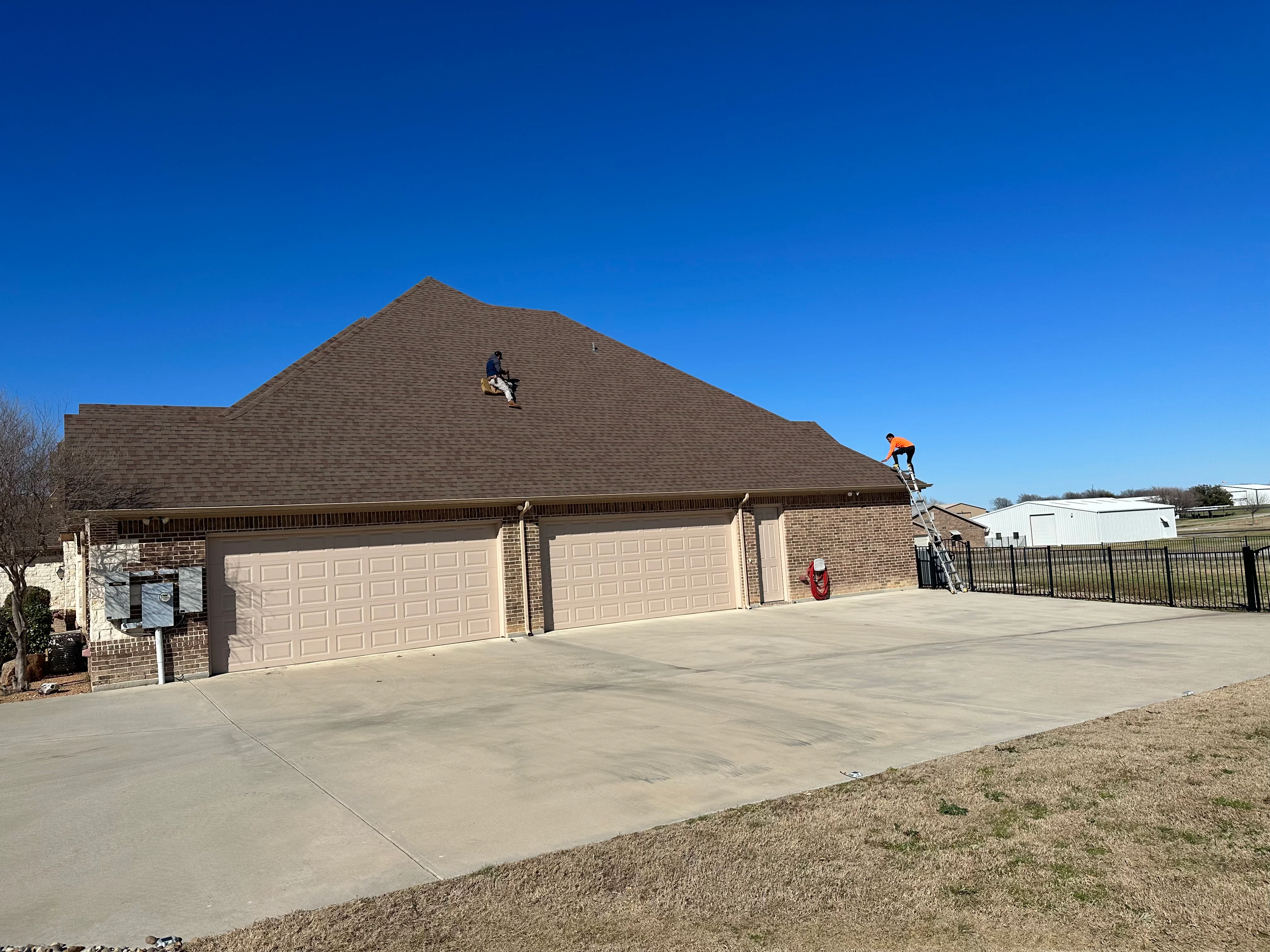 Charcoal gray architectural shingles installed on pitched residential roof with brick home
