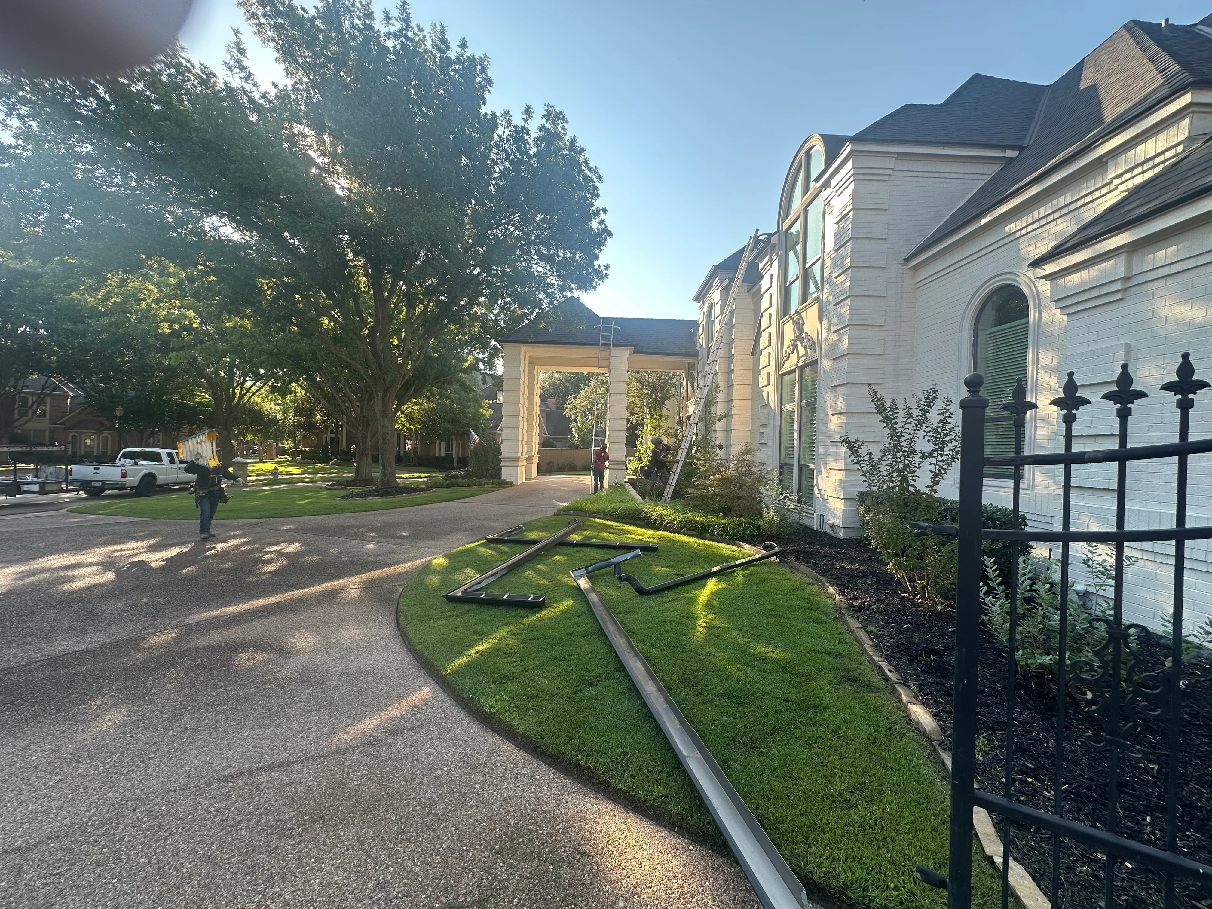 Newly sodded lawn with metal edging, mulch beds, and black iron fence at institutional building