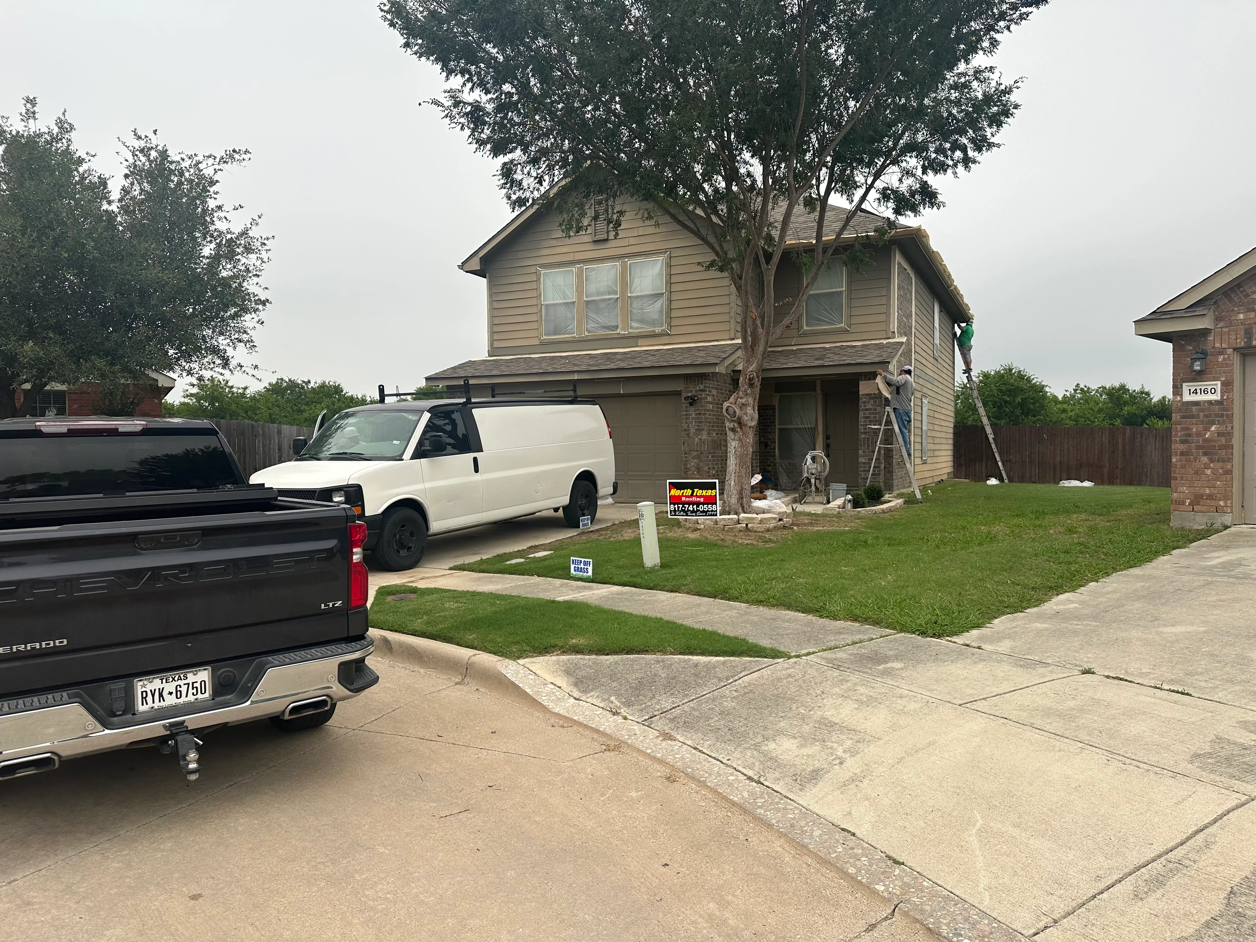 Roofing contractor inspecting two-story home roof with ladder and assessment equipment