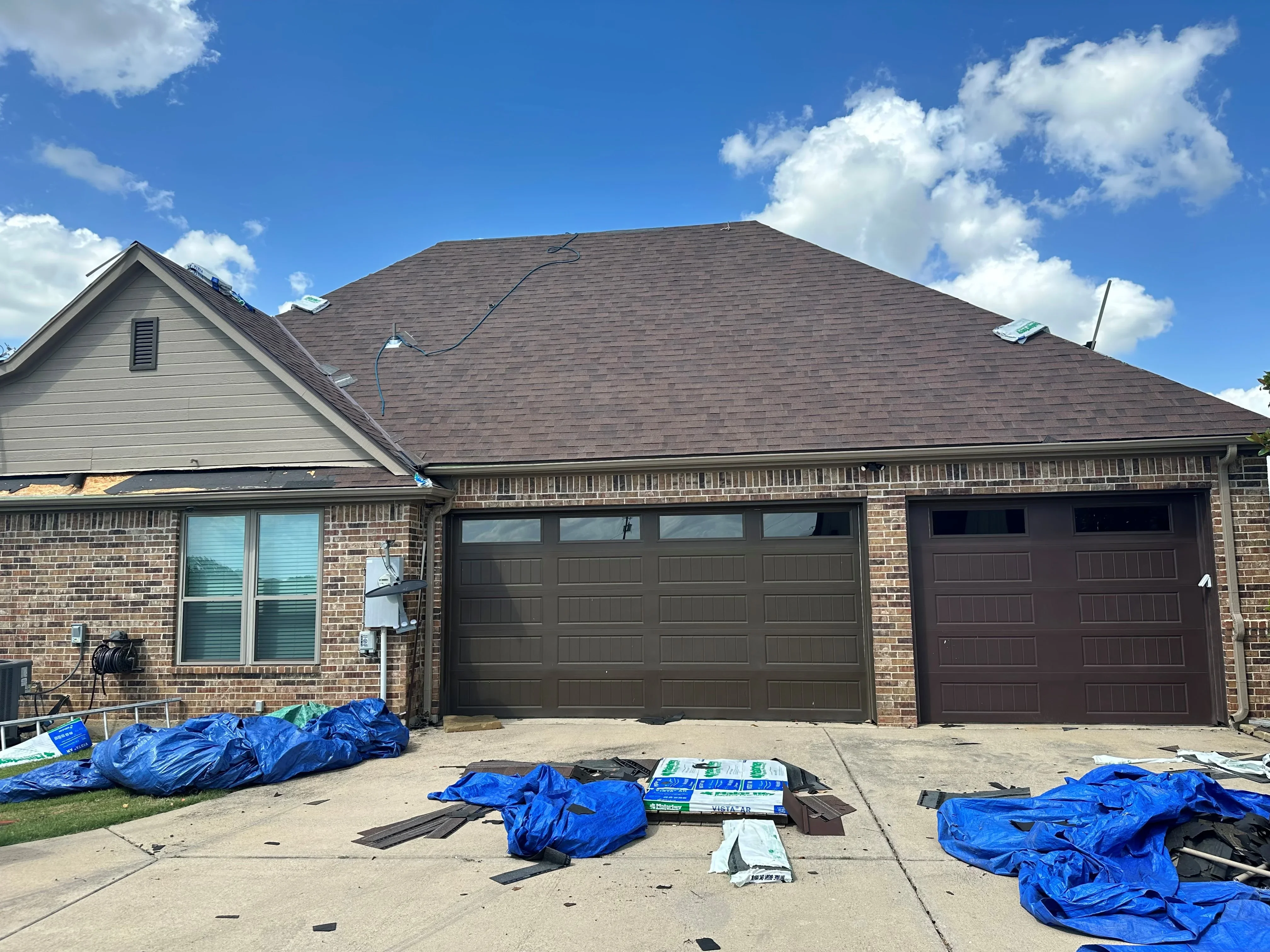New charcoal gray asphalt shingle roof installed on brick residential home with gable design