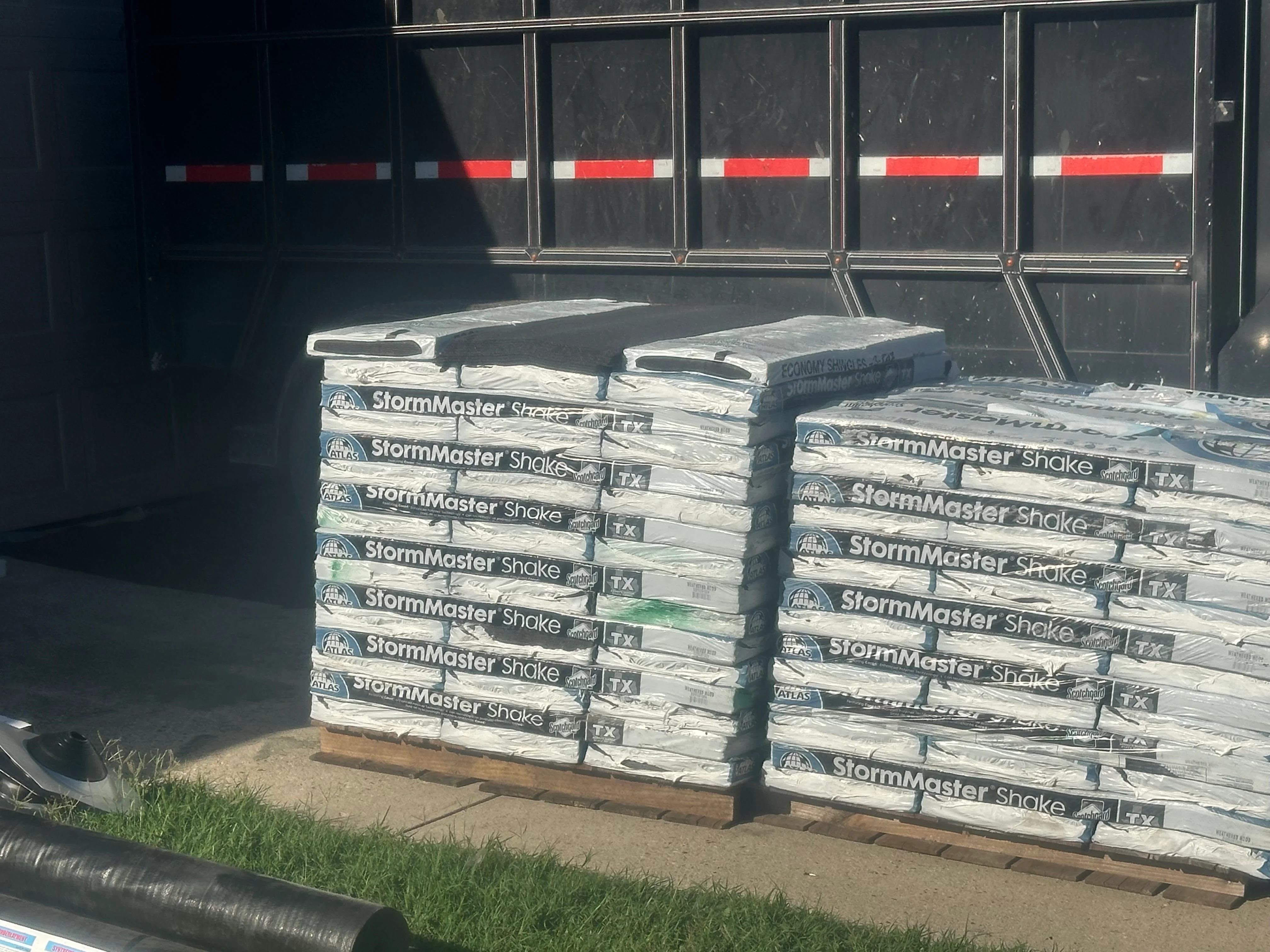 Stacked pallets of StormMaster Shake roofing shingles staged for installation