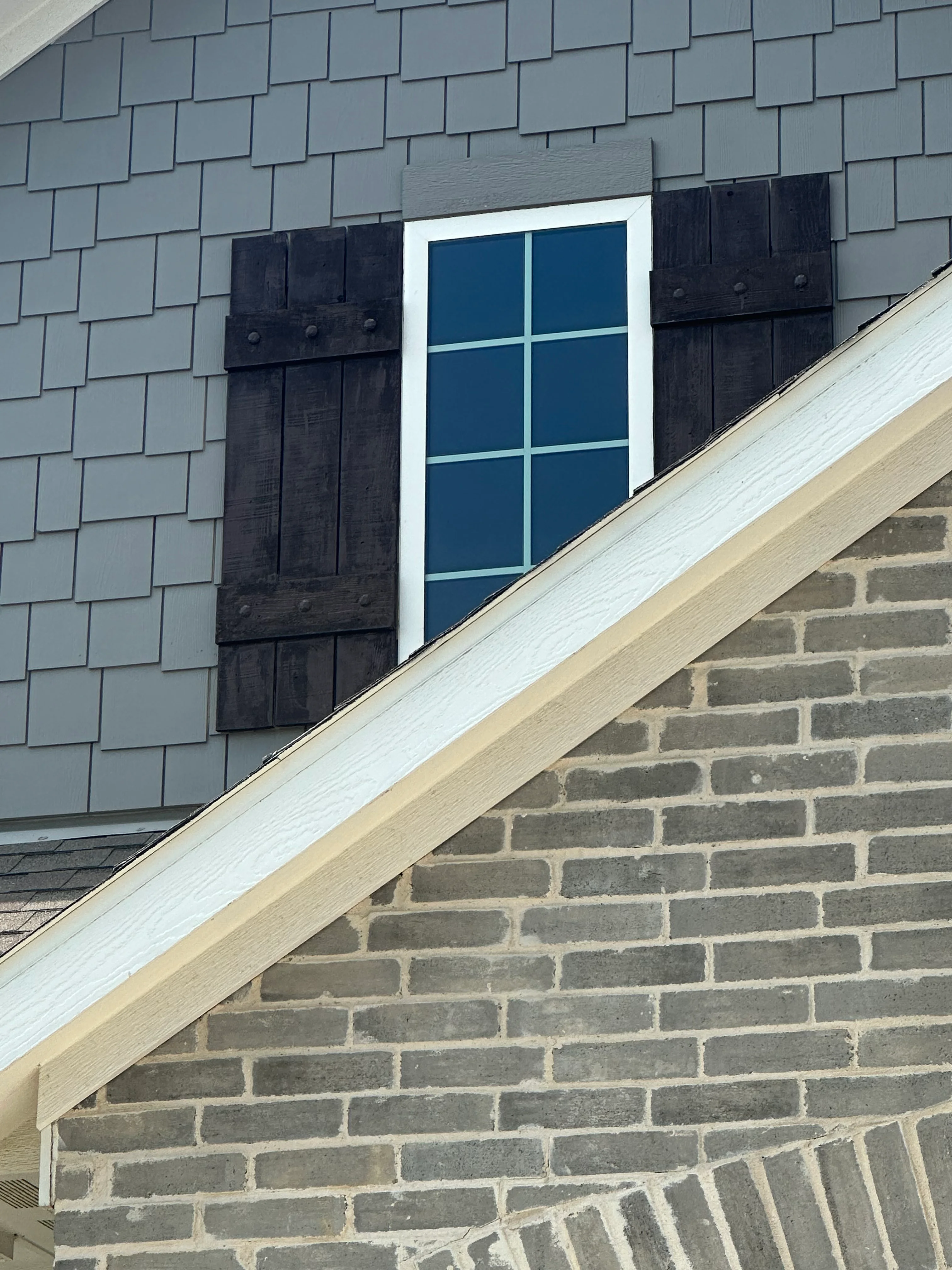 Gray architectural shingles on gable roof with white fascia trim and black shutters