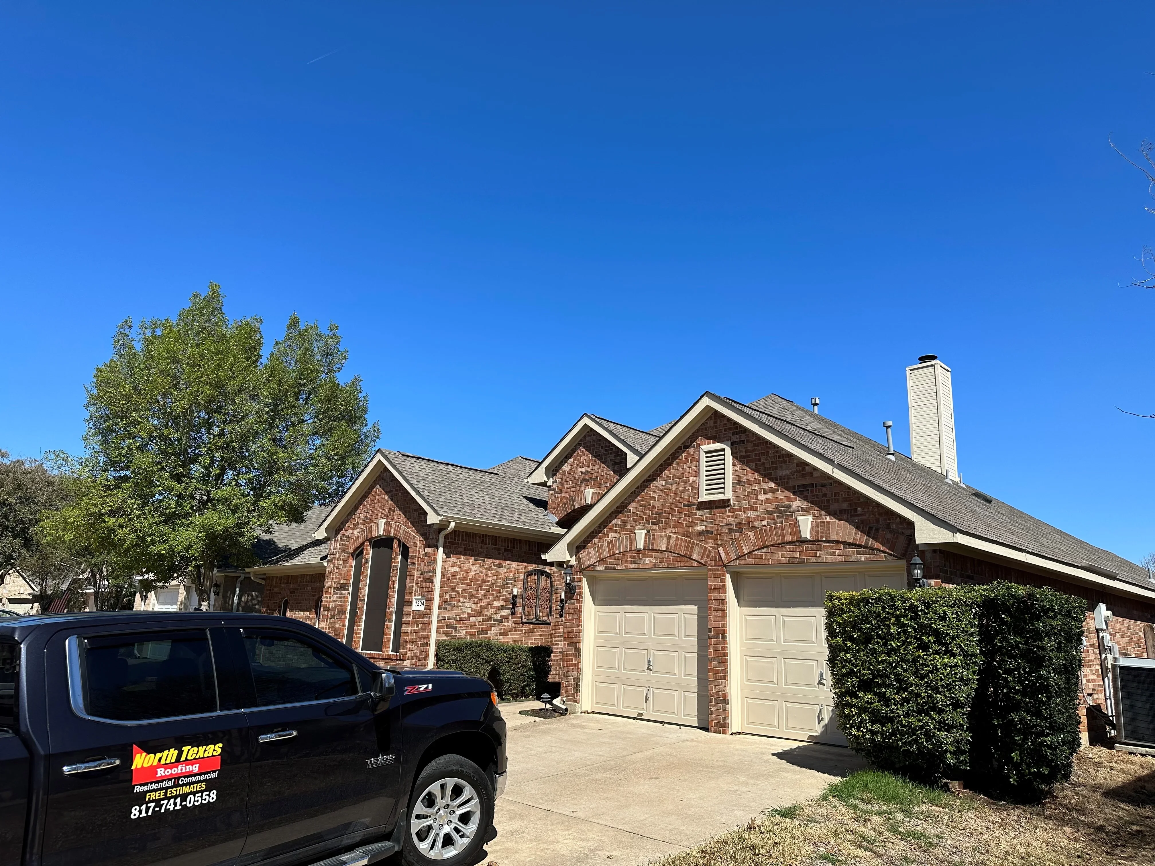 Brick home with new gray architectural shingle roof and cream chimney cap