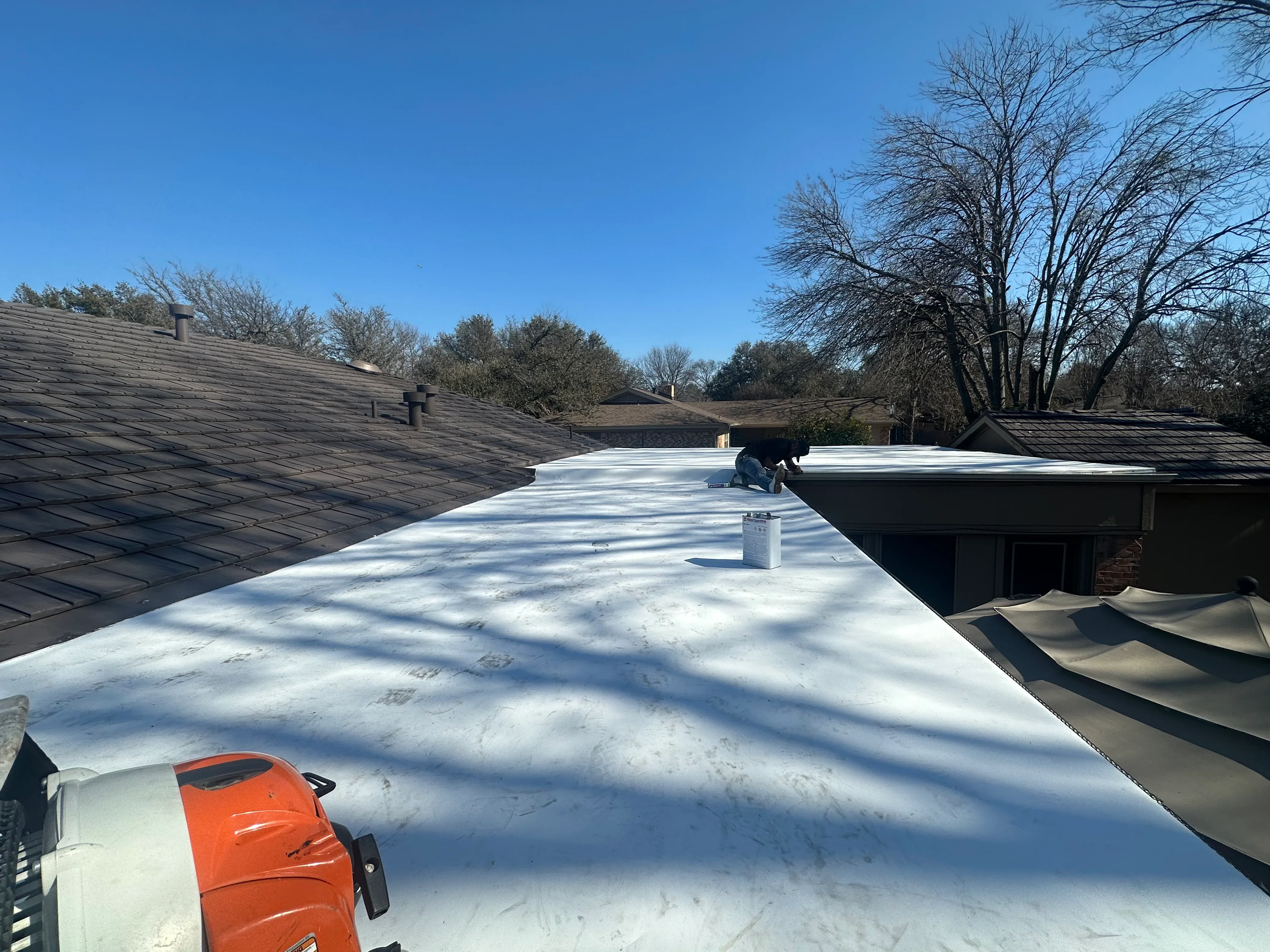 White TPO membrane flat roof installation with equipment and multiple roof sections visible