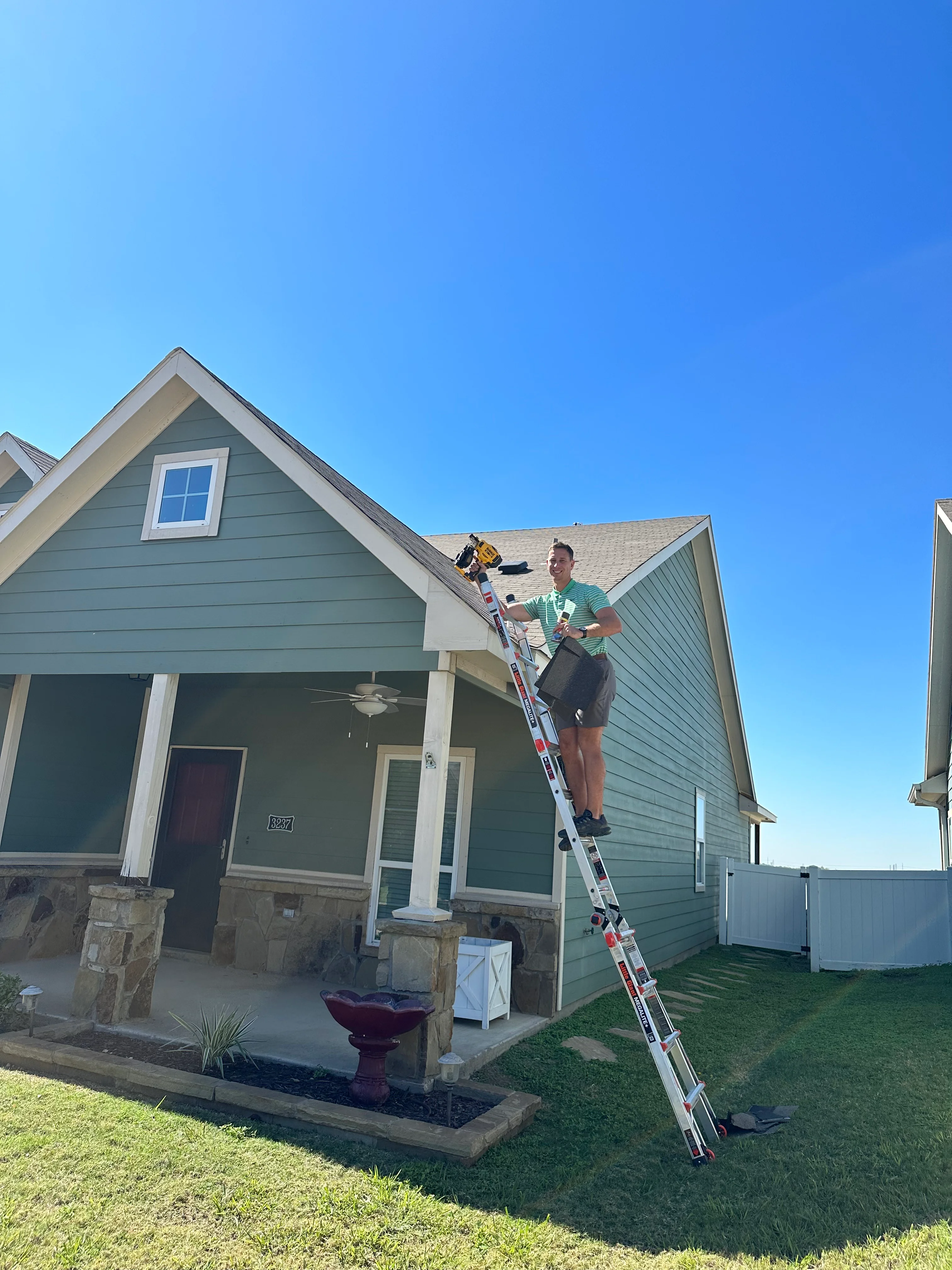 Technician on ladder inspecting composite shingle roof of residential home