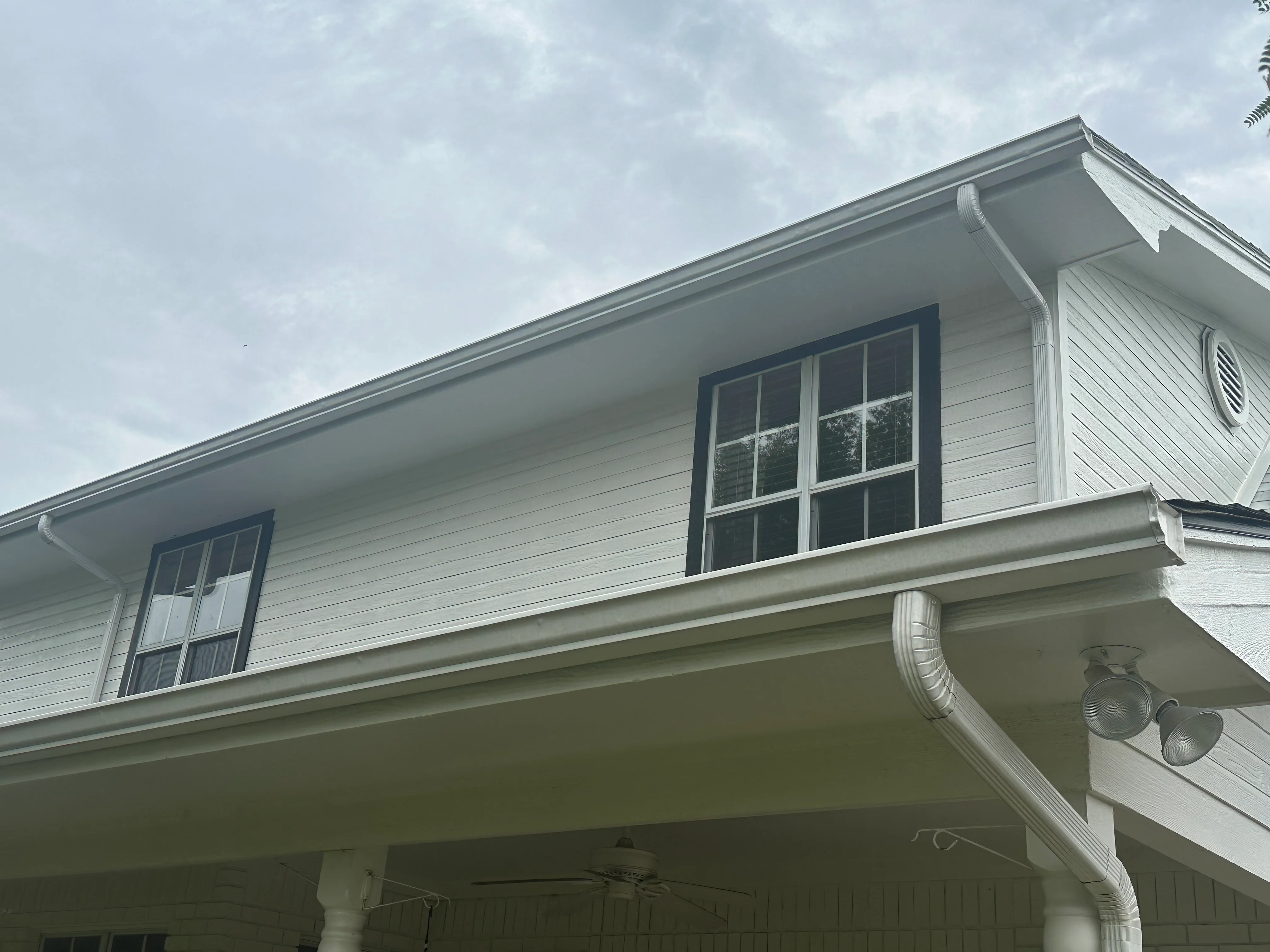 White vinyl soffit and fascia with integrated gutters and downspouts on residential home