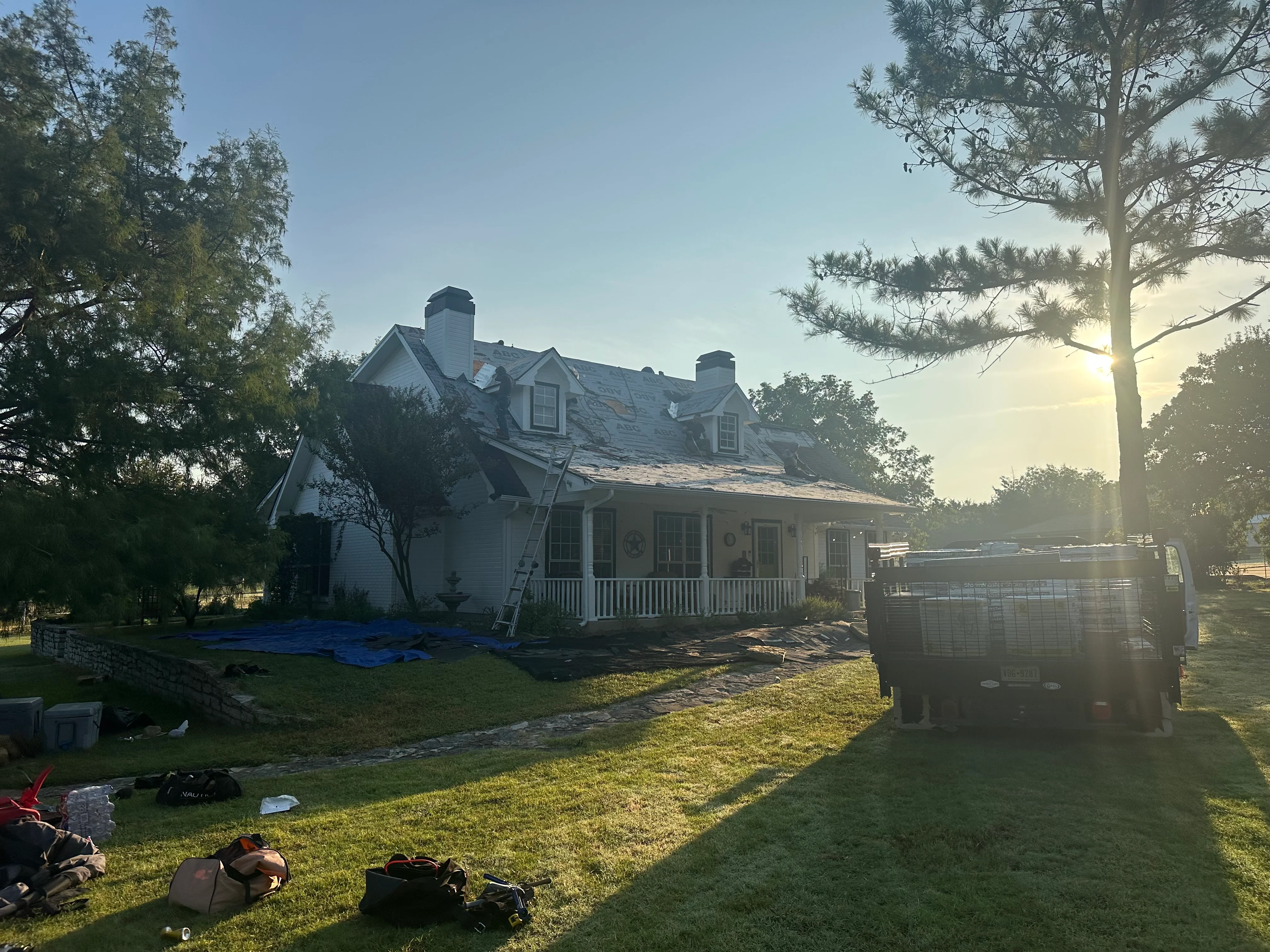 Two-story home with new asphalt shingle roof installation, dormers, and dual chimneys