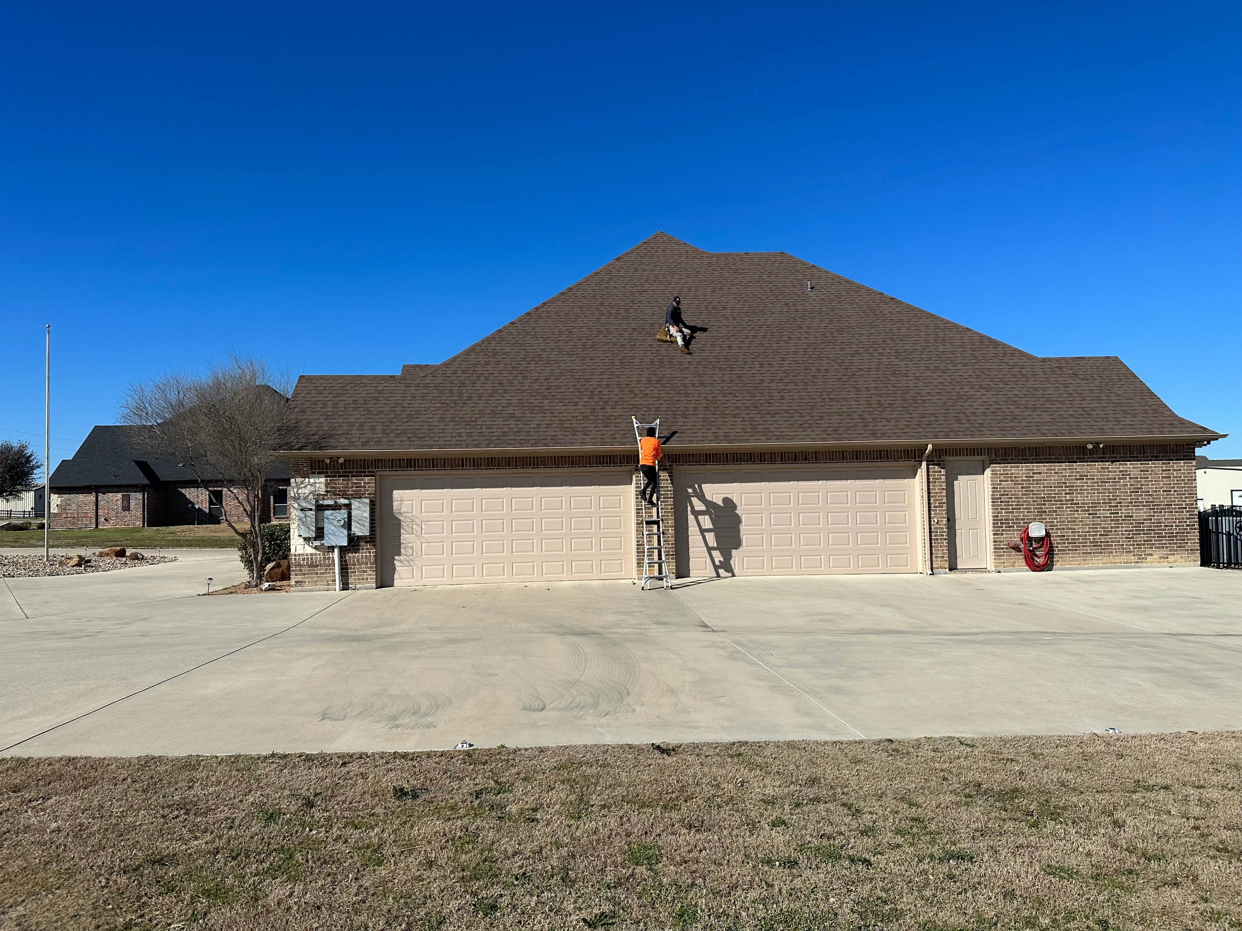 Gray architectural shingles installed on hip roof of brick residential home
