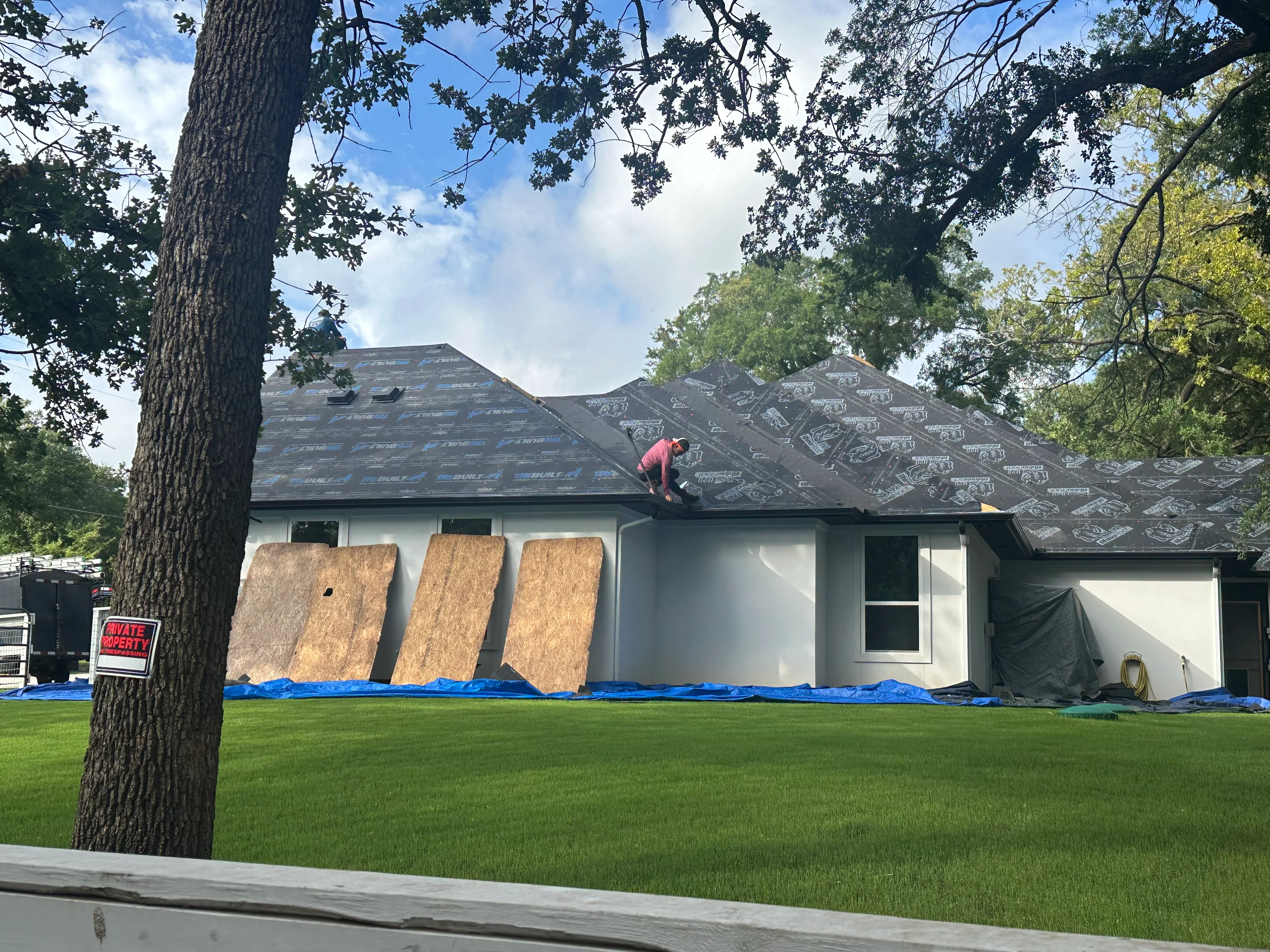 Roofer installing architectural shingles on residential home with protective underlayment visible