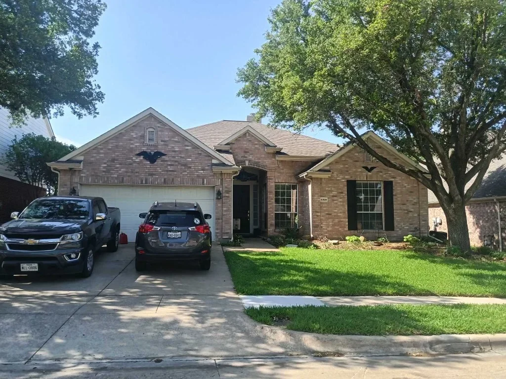 Two-story brick home with new architectural shingle roof installation, tan-colored shingles with gable vents