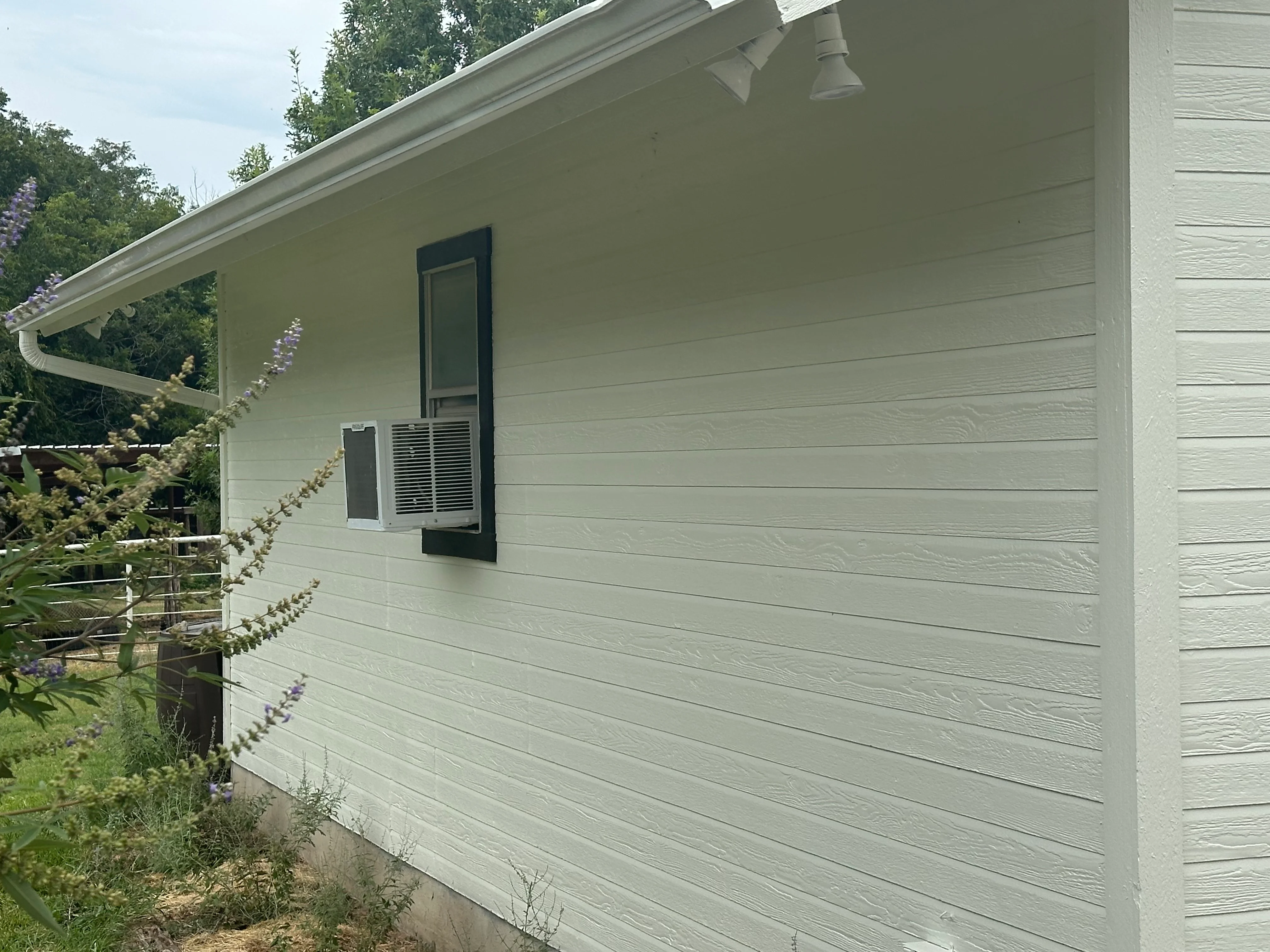 White fiber cement soffit and fascia with horizontal siding, gutters, and soffit vents on residential structure