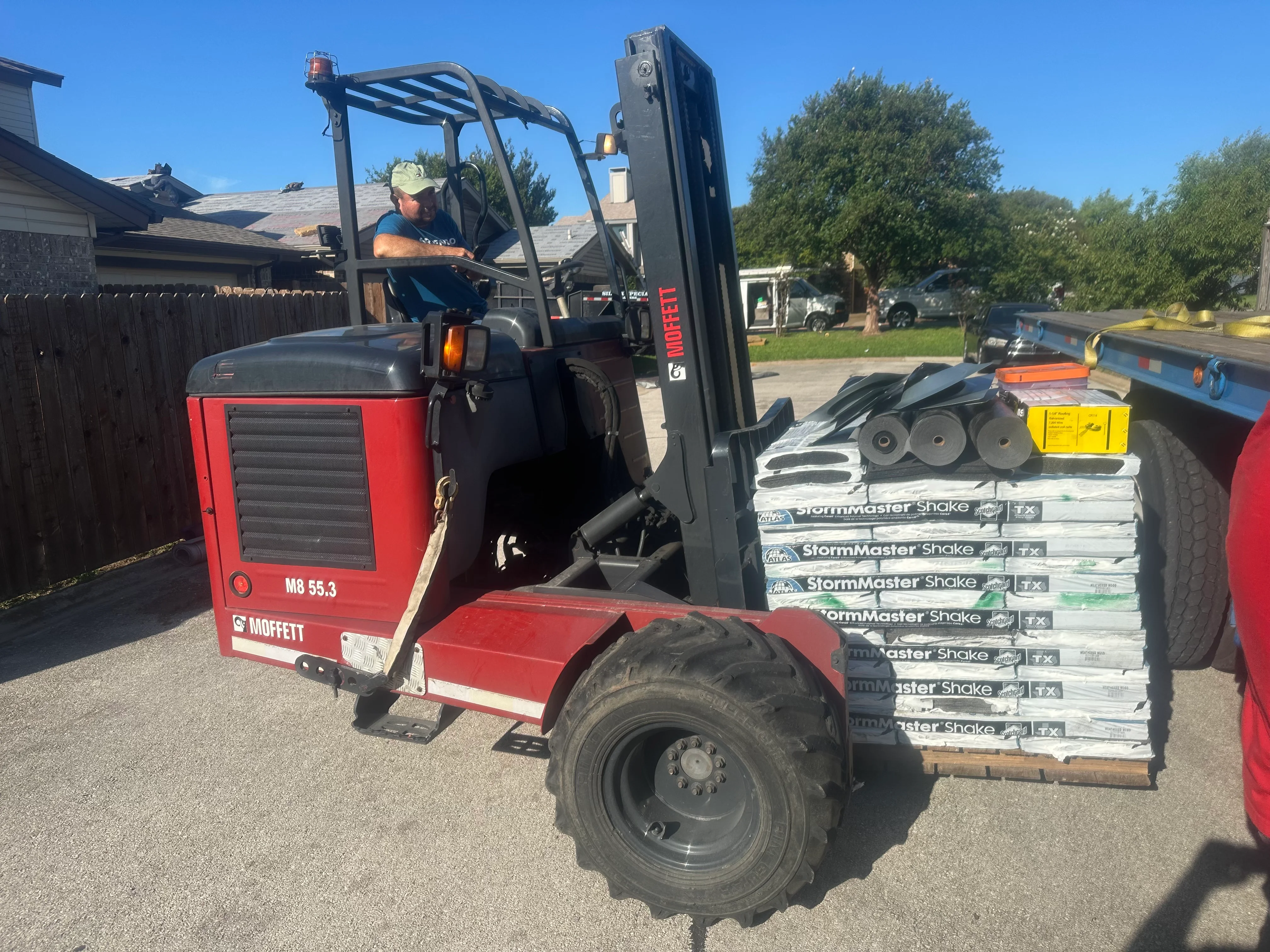 Forklift loading StormMaster Shake shingle bundles at residential roofing project site