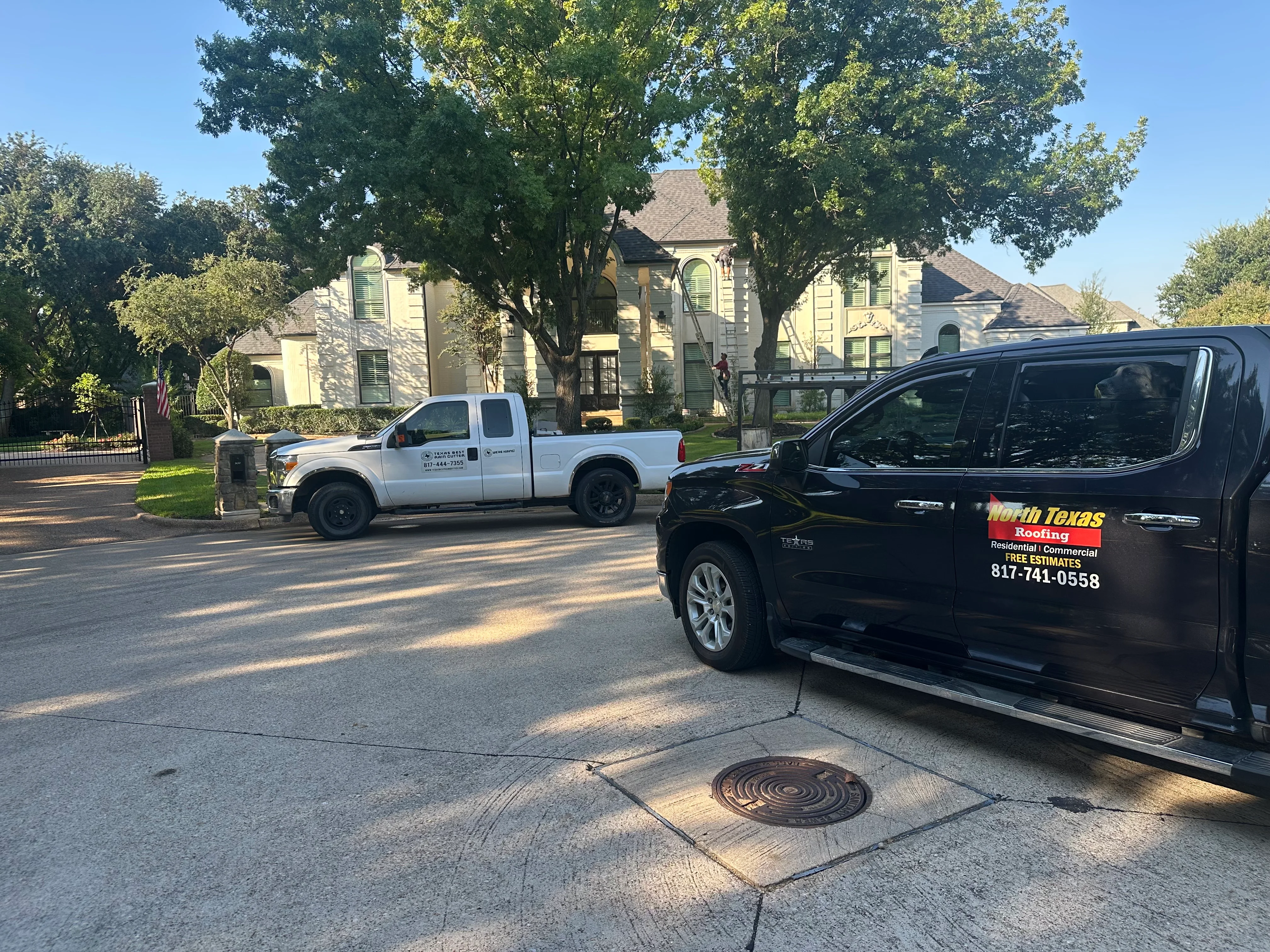 Roofing contractor vehicles at residential home with stone exterior and asphalt shingle roof