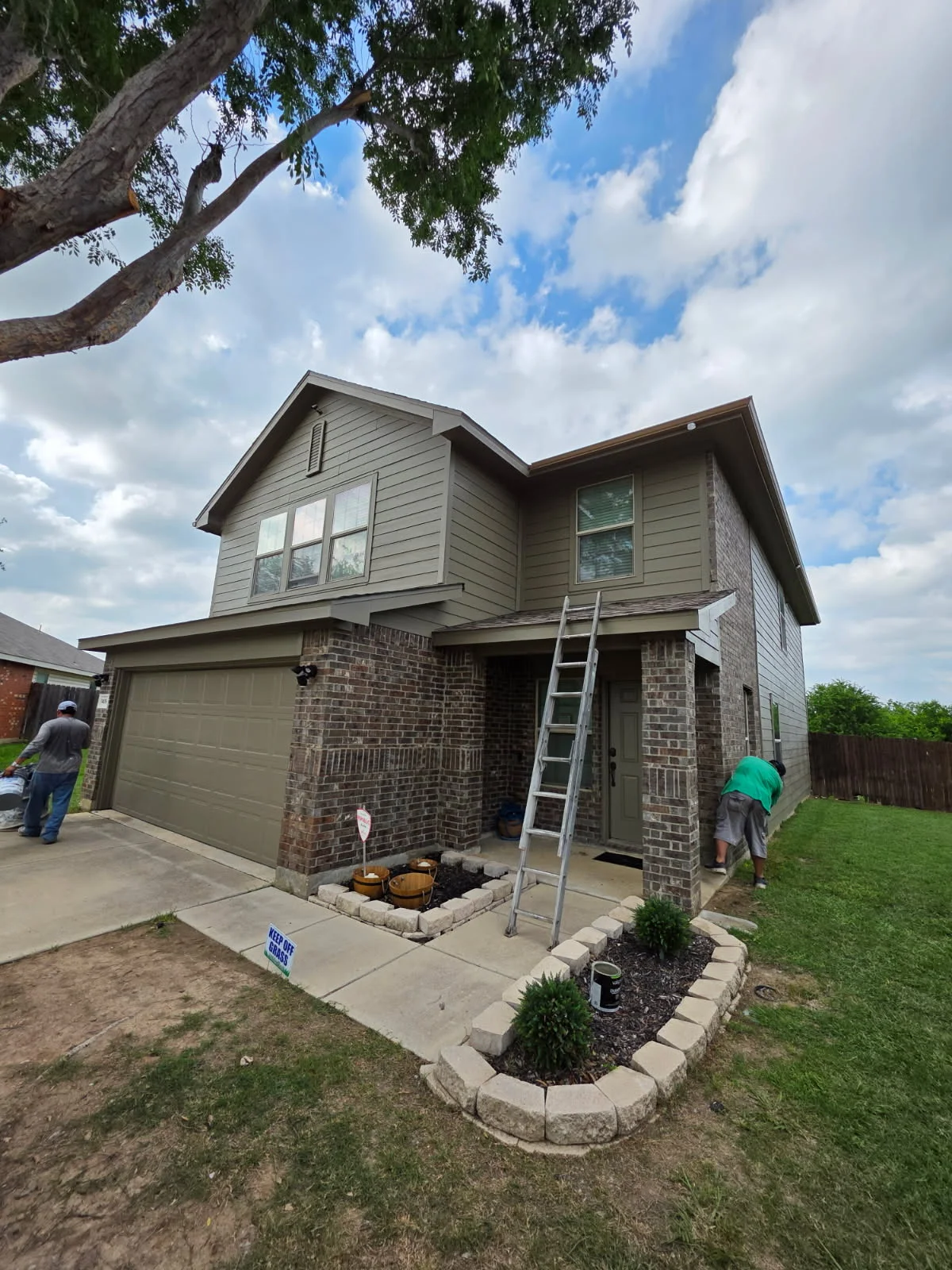 Two-story brick home with ladder positioned for roof inspection and assessment work