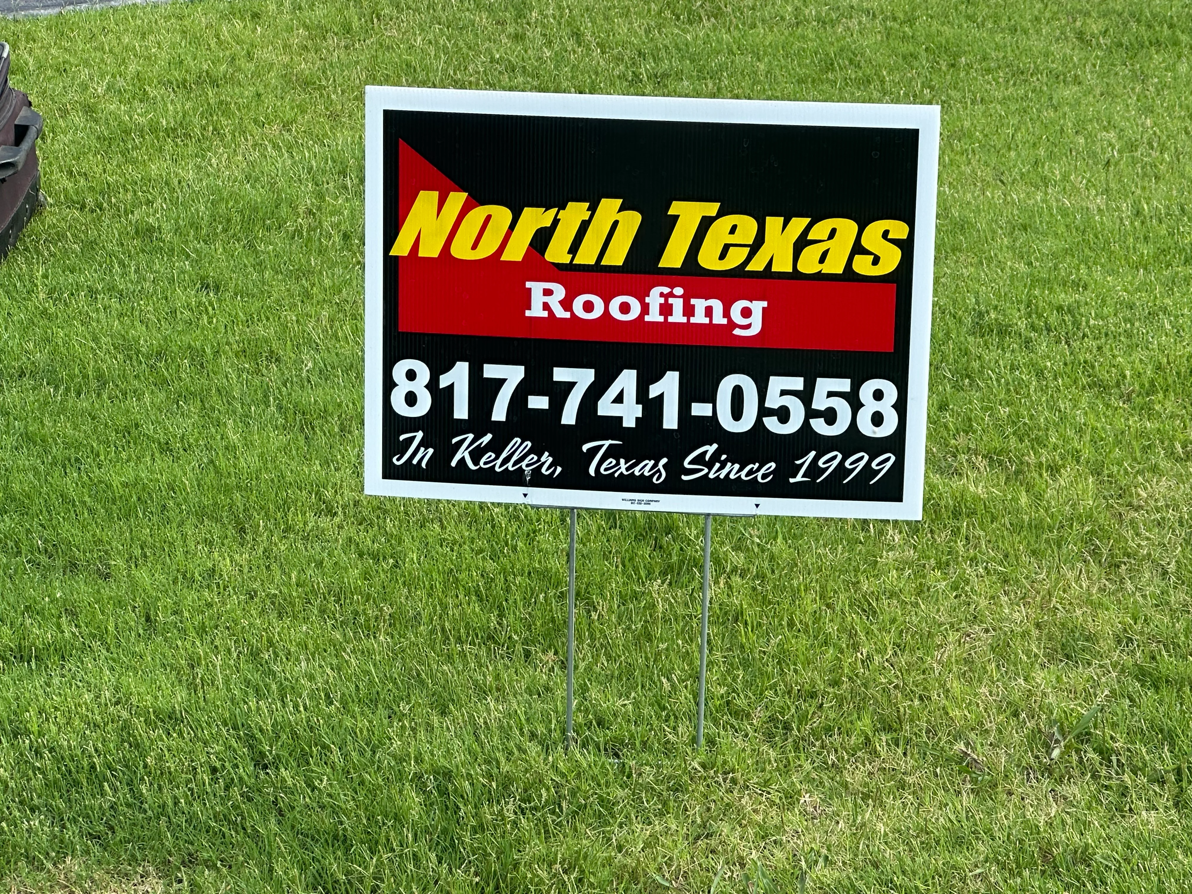 Custom yard sign with yellow and red design on metal stakes in grass