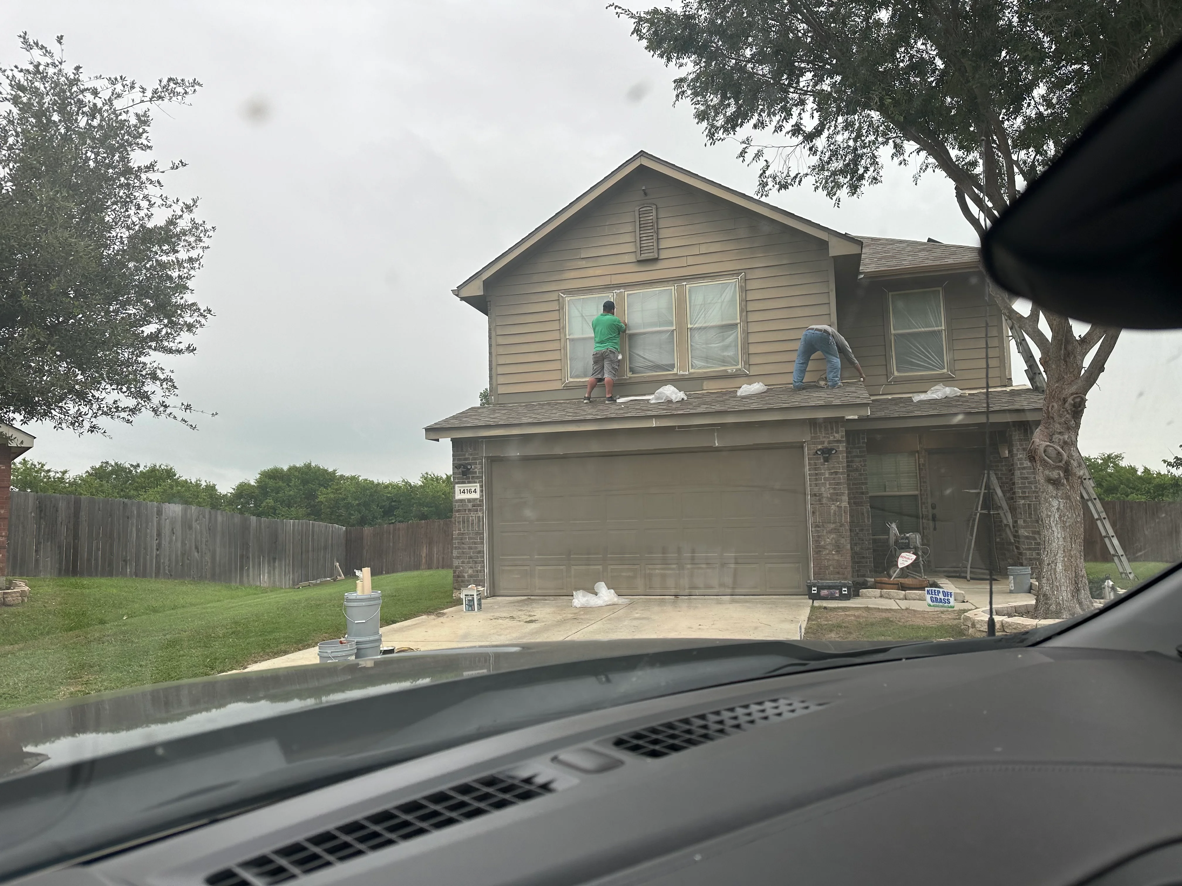 Workers installing new roofing materials on two-story residential home with brick and siding exterior