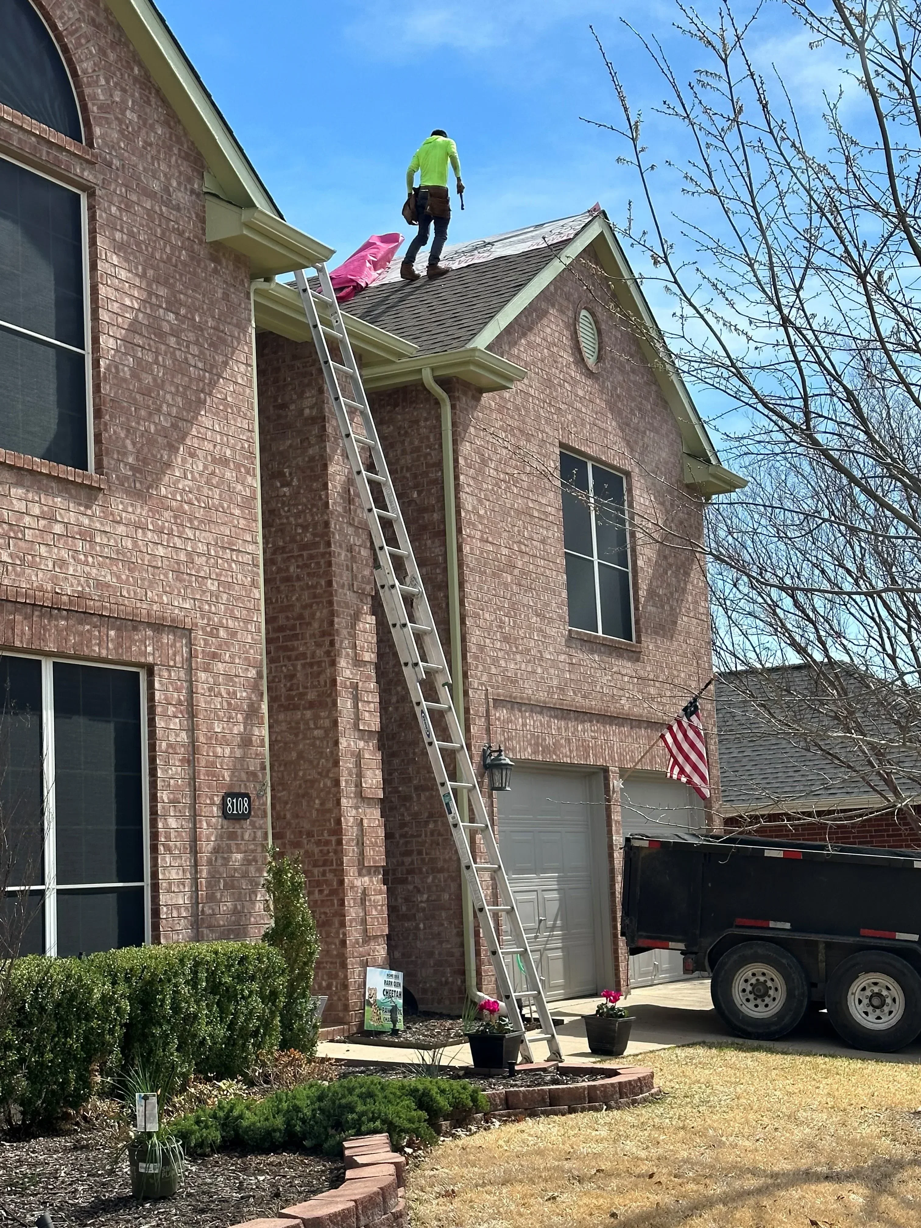Two-story brick home with newly installed brown asphalt shingle roof and metal flashing