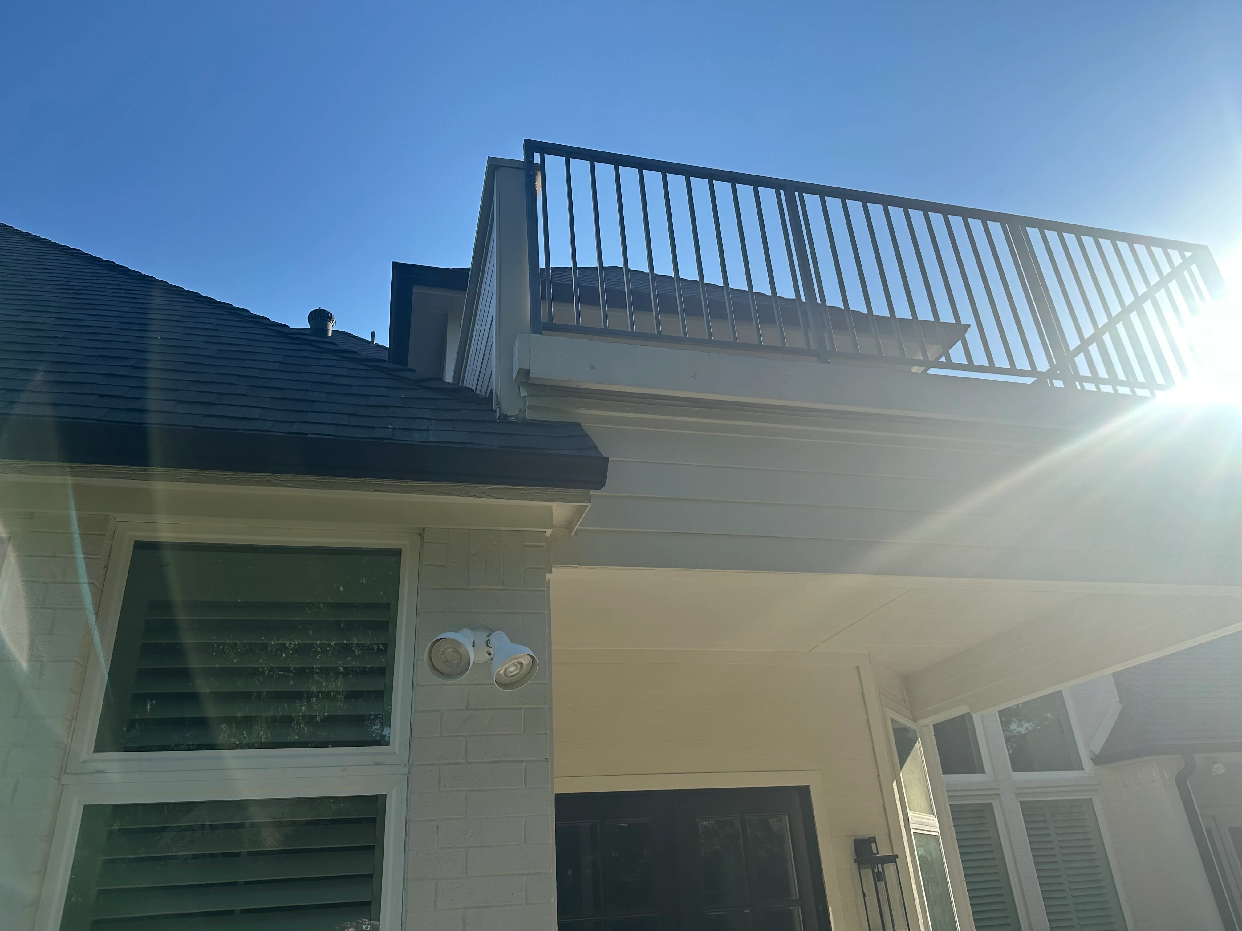 Second-story deck with metal railing, new roof framing, and white fascia on residential home