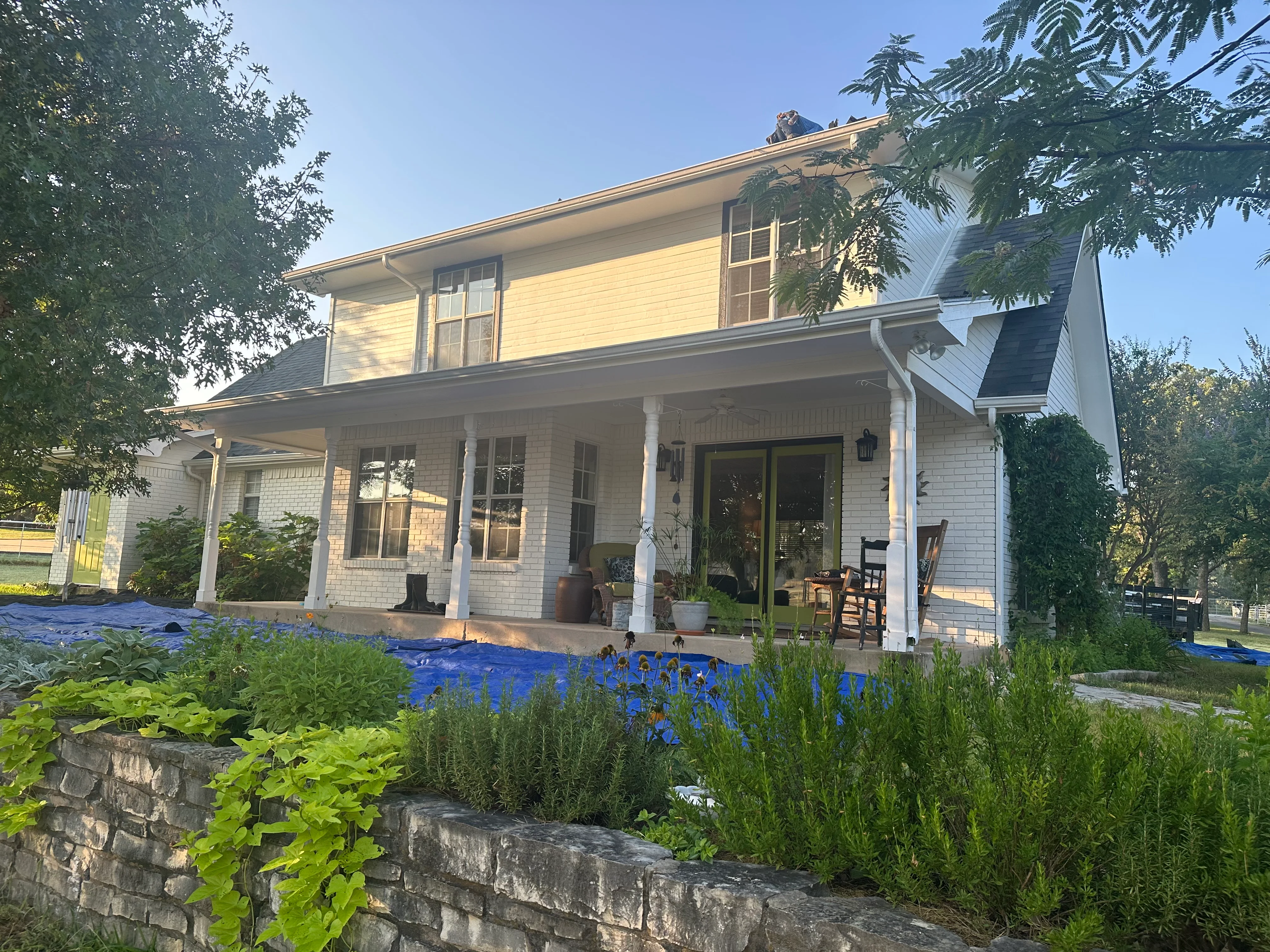 Two-story white farmhouse with new roof, white columns, and updated gutters
