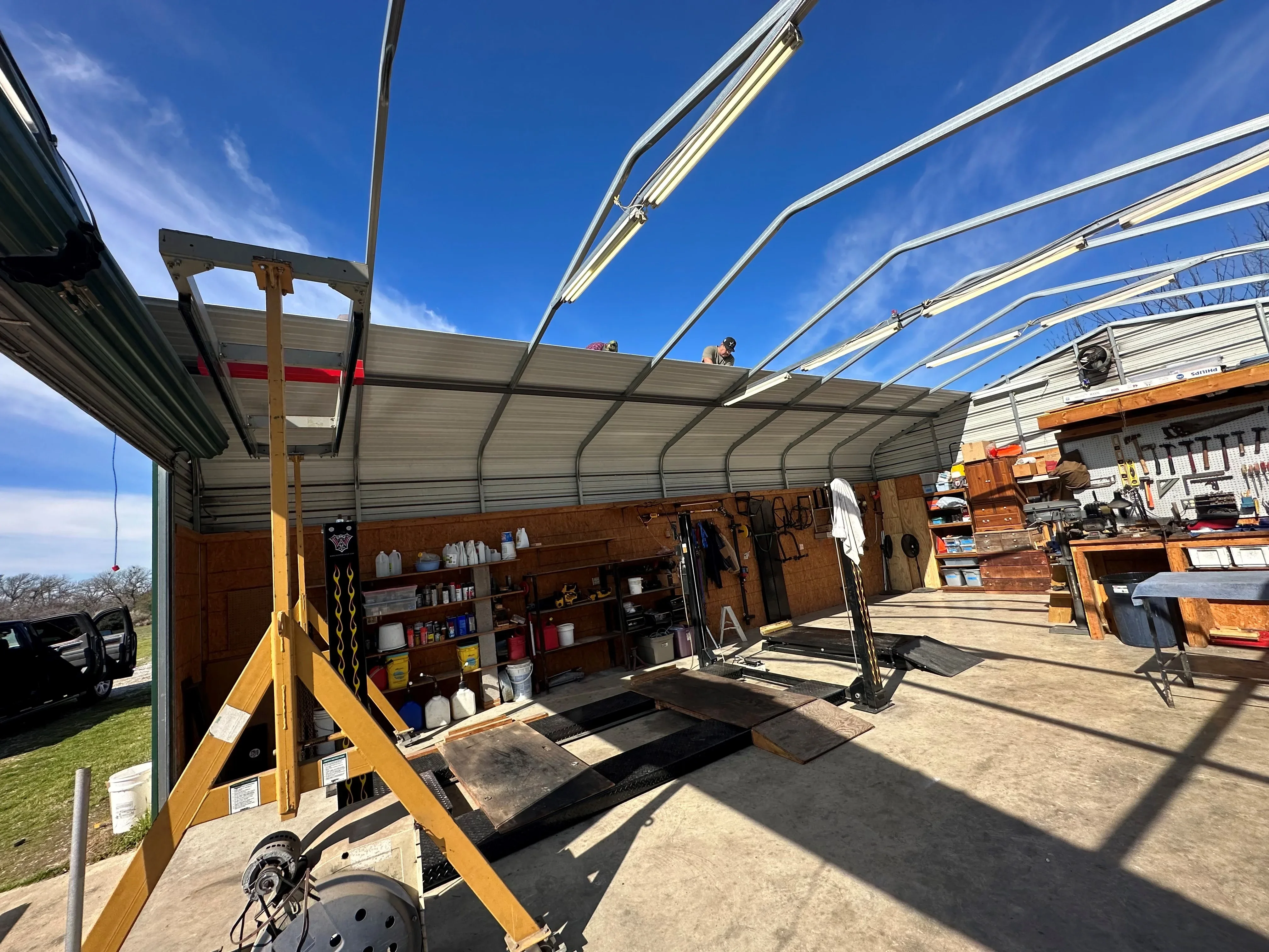 Steel-framed polycarbonate canopy with arched beams over commercial work area