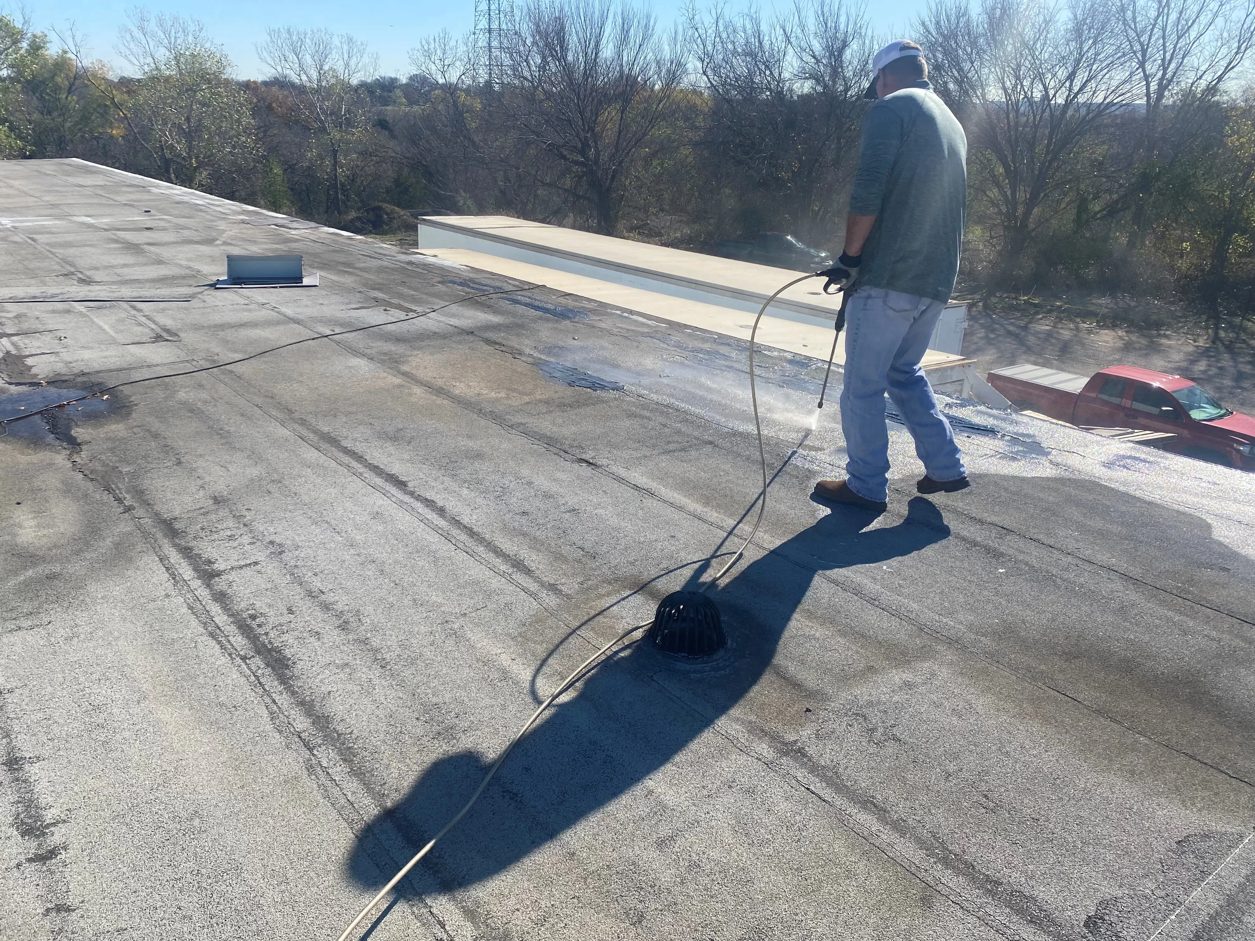 Roofer installing flashing on flat tar and gravel roof with maintenance work in progress