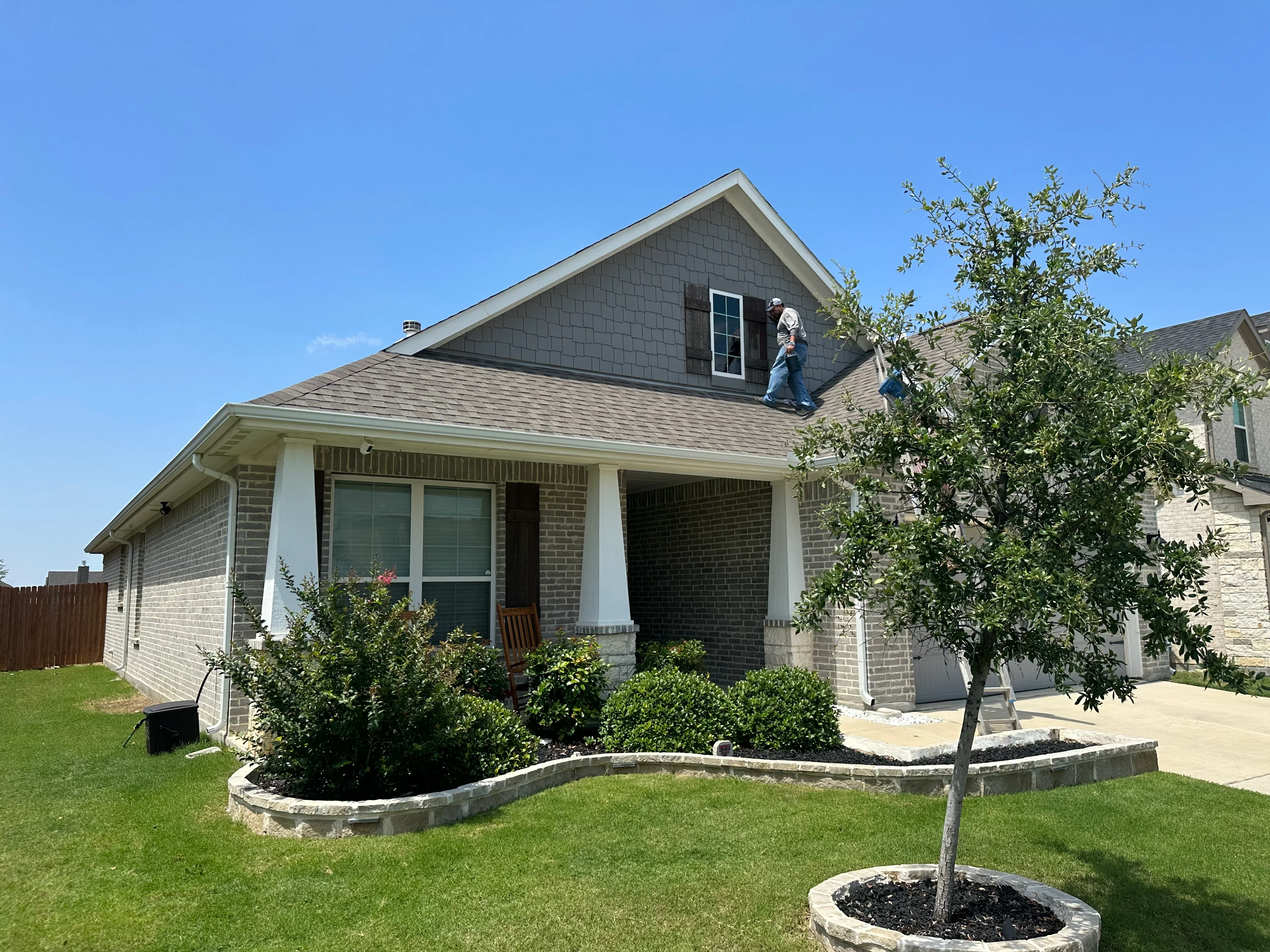 New gray architectural shingle roof on brick home with white trim and gable vent