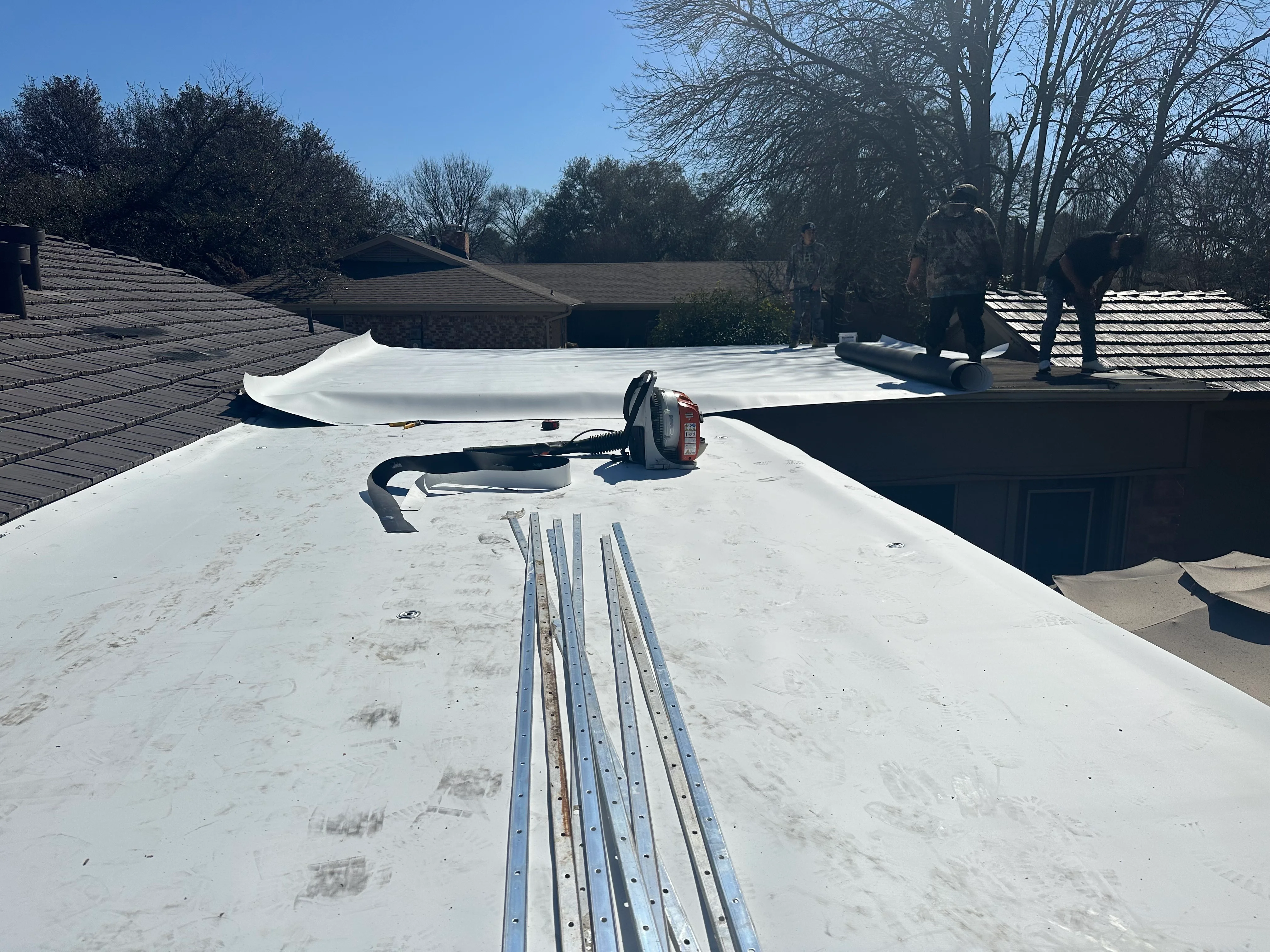 White TPO membrane installation with metal trim and fasteners on flat roof