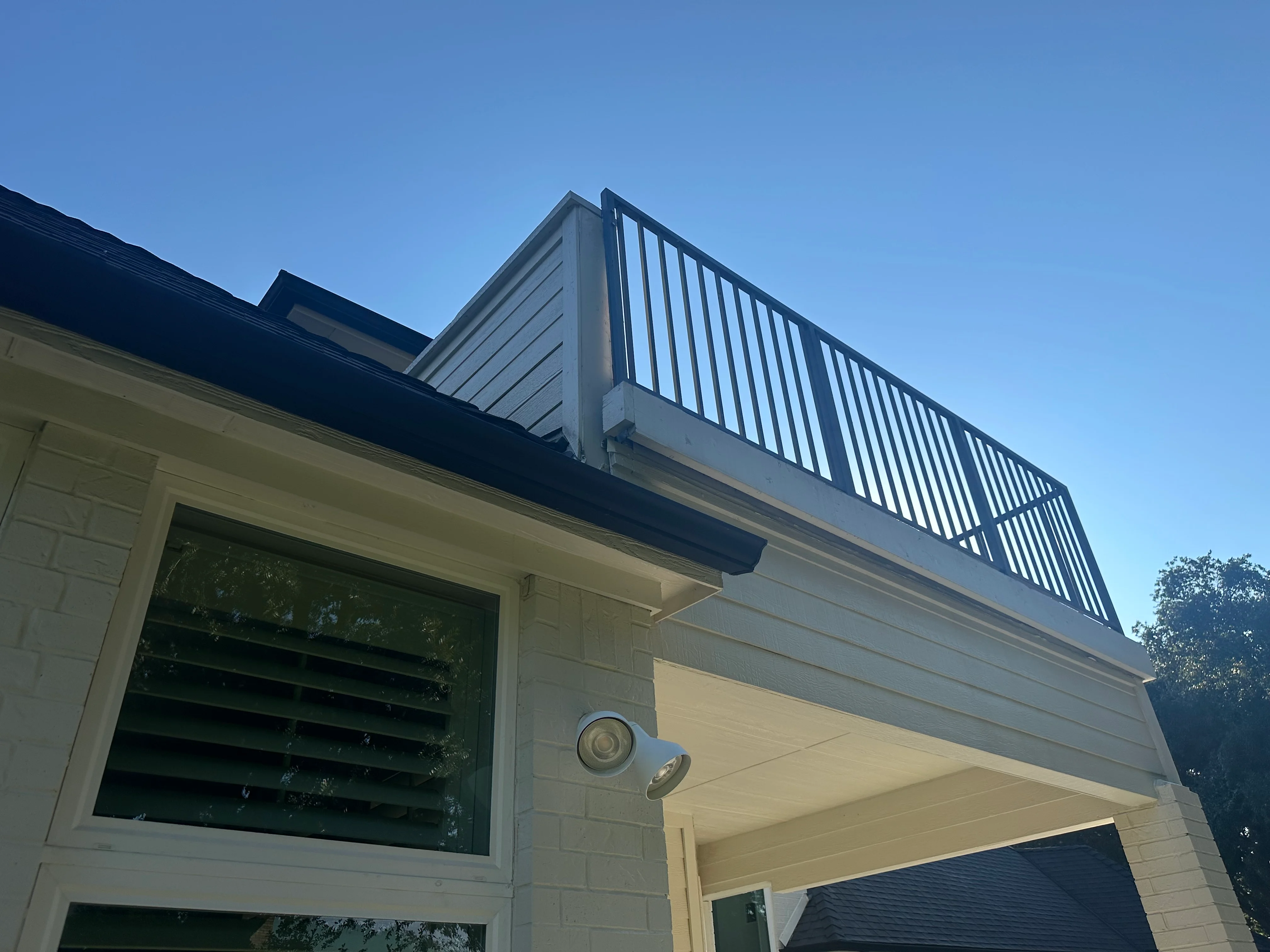 Second-story deck with metal railing, dark roof, white fascia, and composite decking