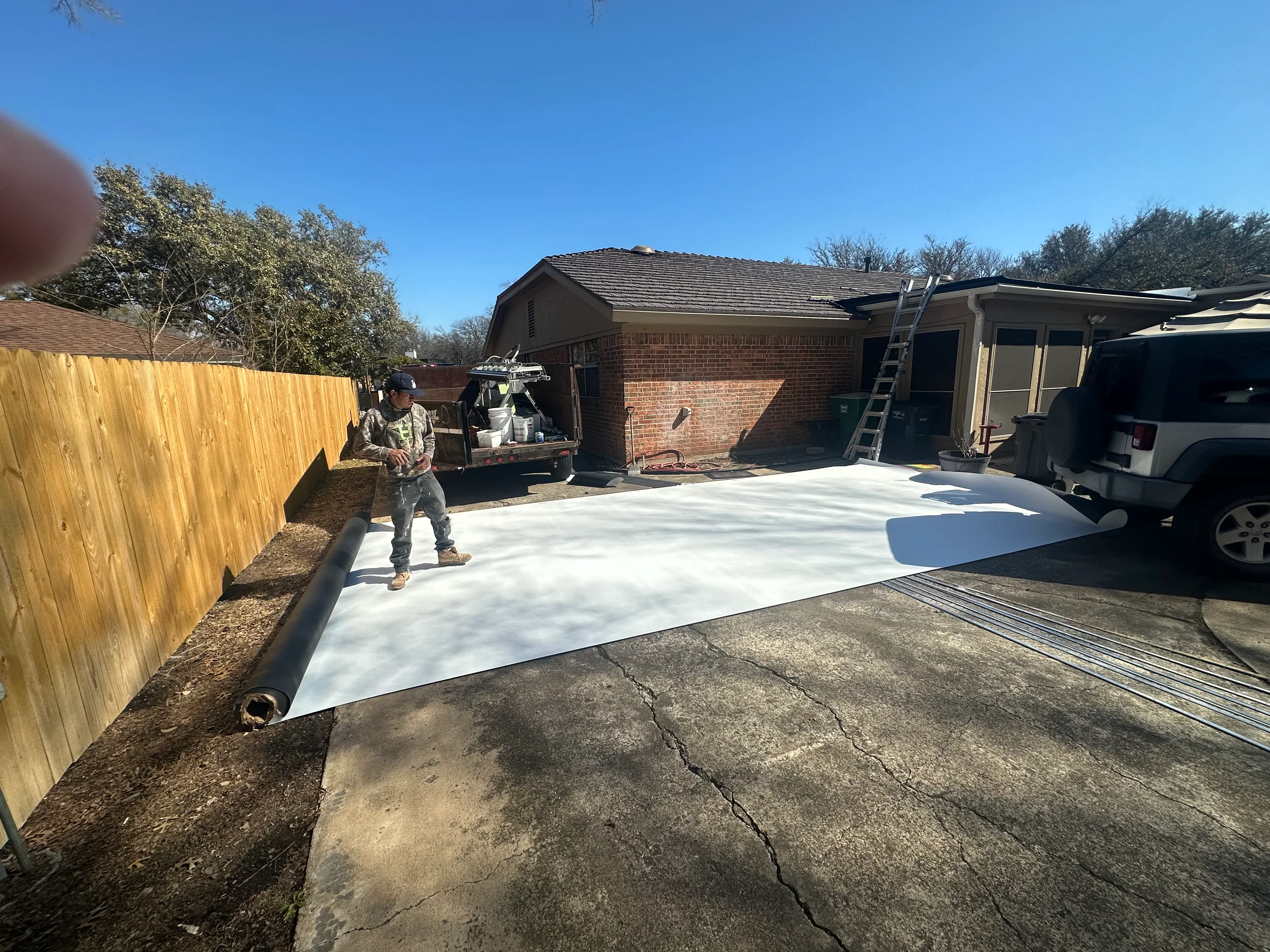 White protective driveway sheeting installed during residential roofing project with ladder access