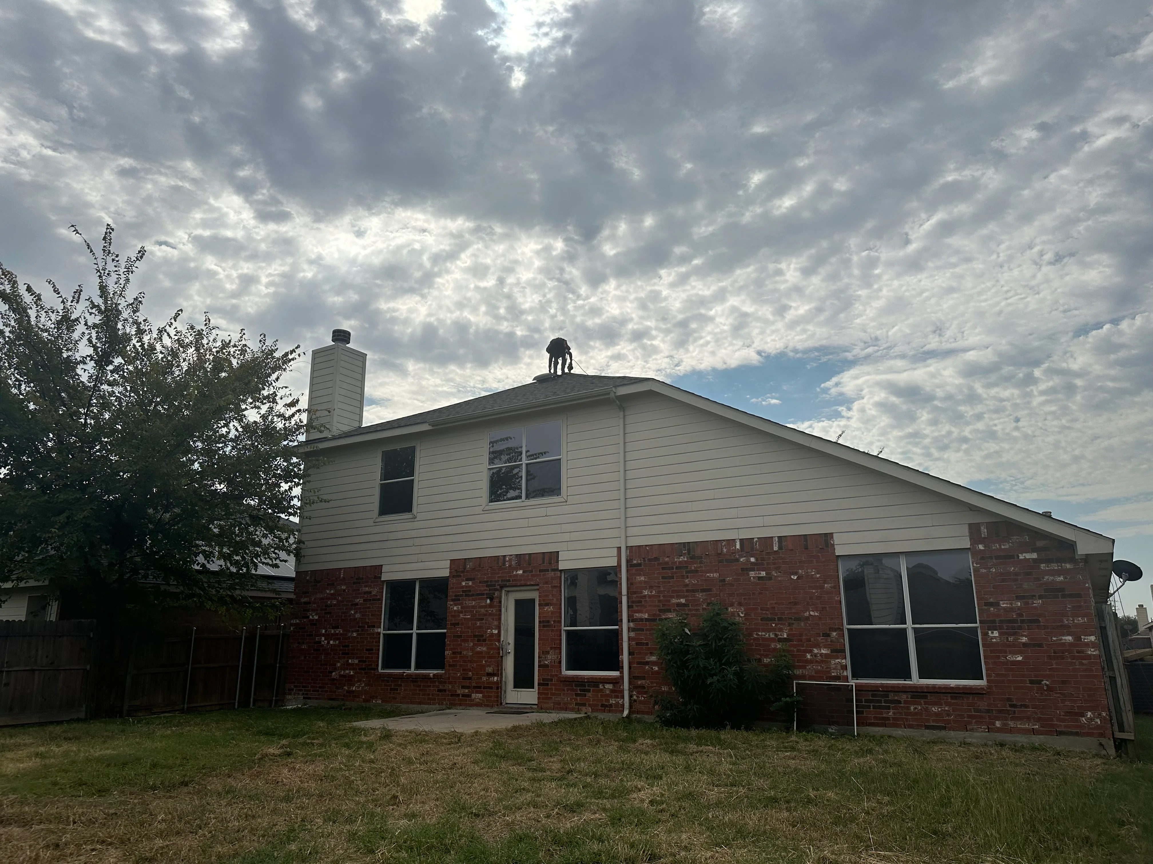 Two-story brick home with new asphalt shingle roof installation and chimney