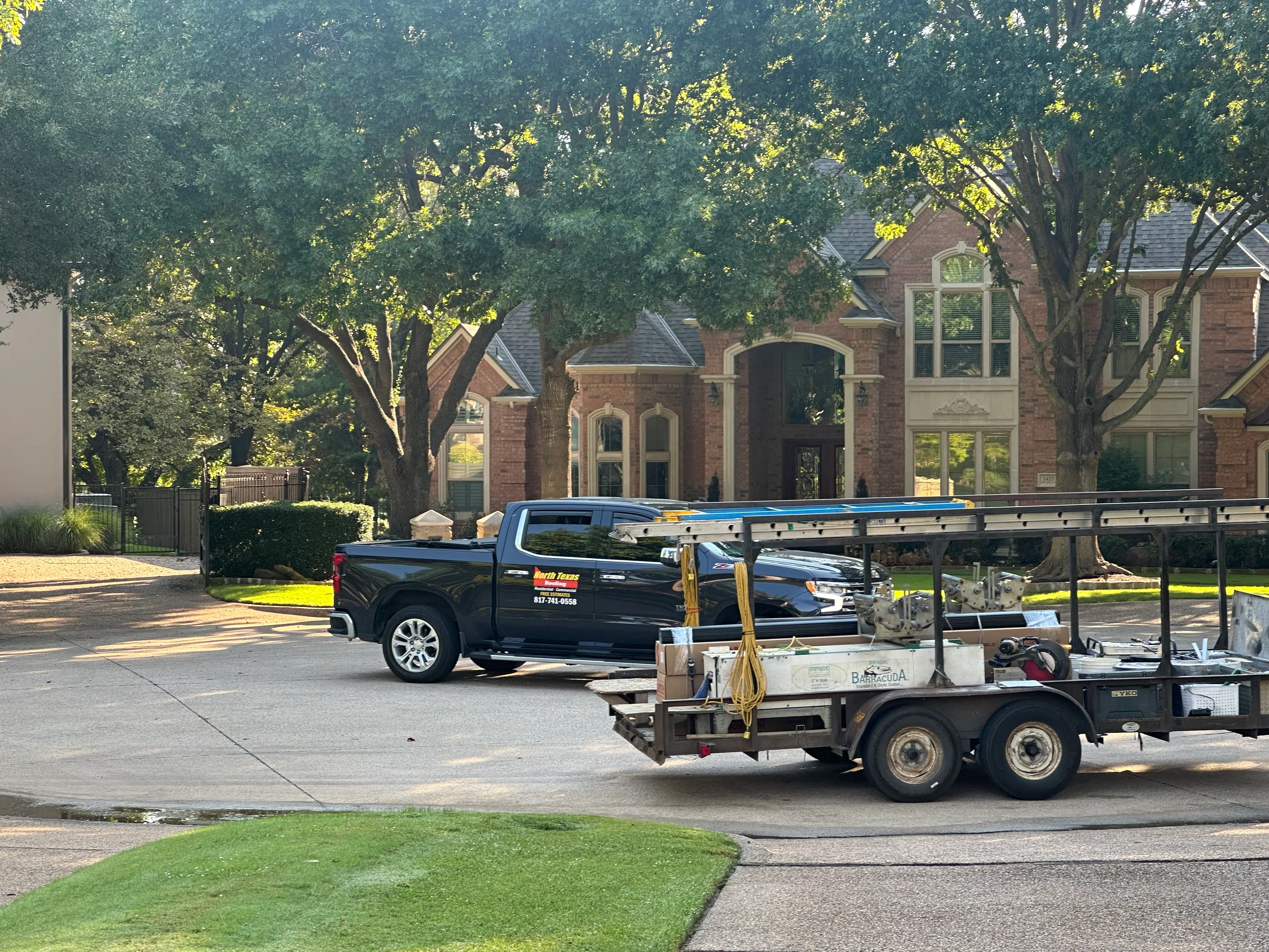 Roofing truck and equipment staged at brick home with multiple roof lines and dormers