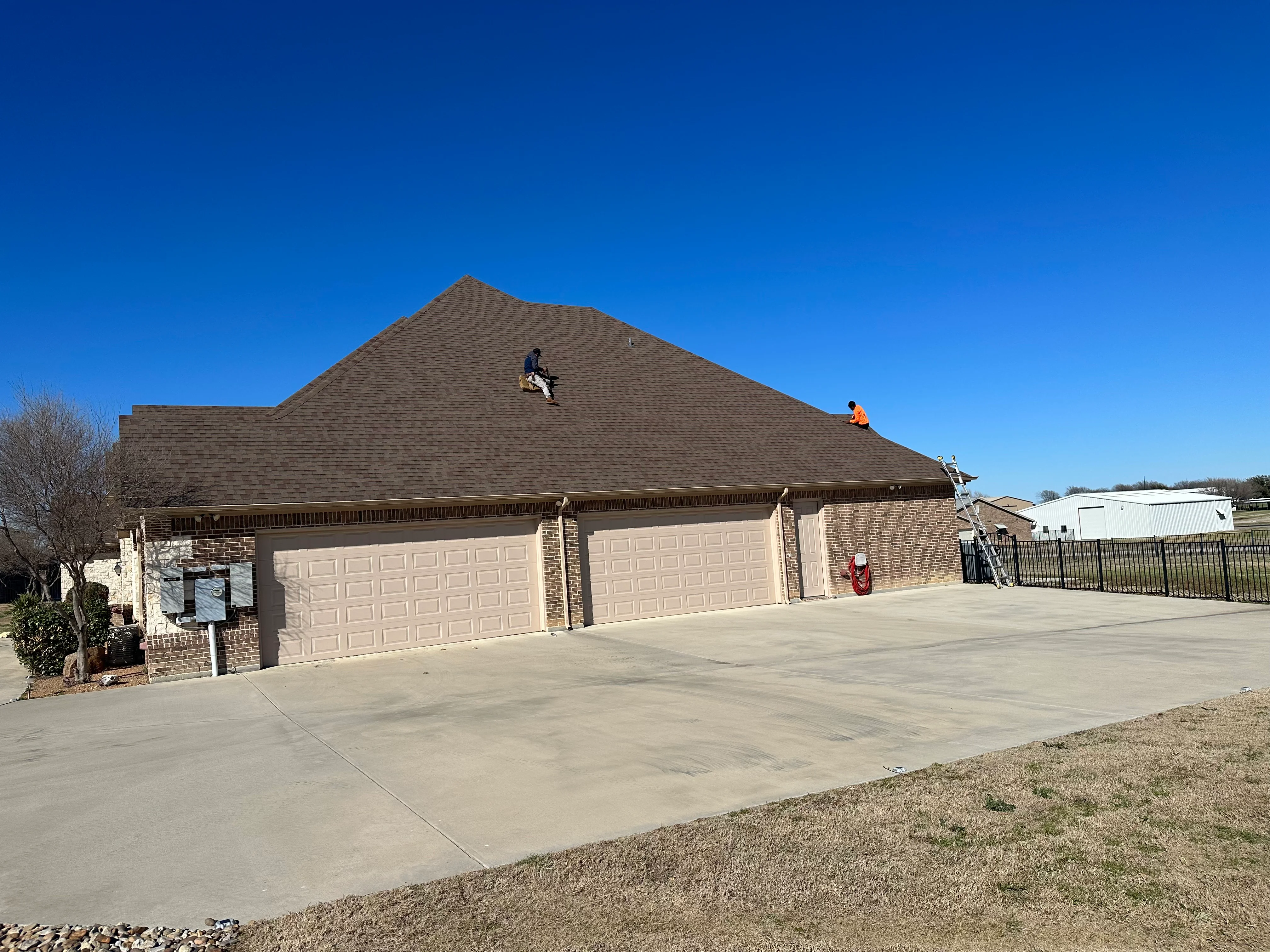 Charcoal gray architectural shingles installed on residential gable roof with brick exterior