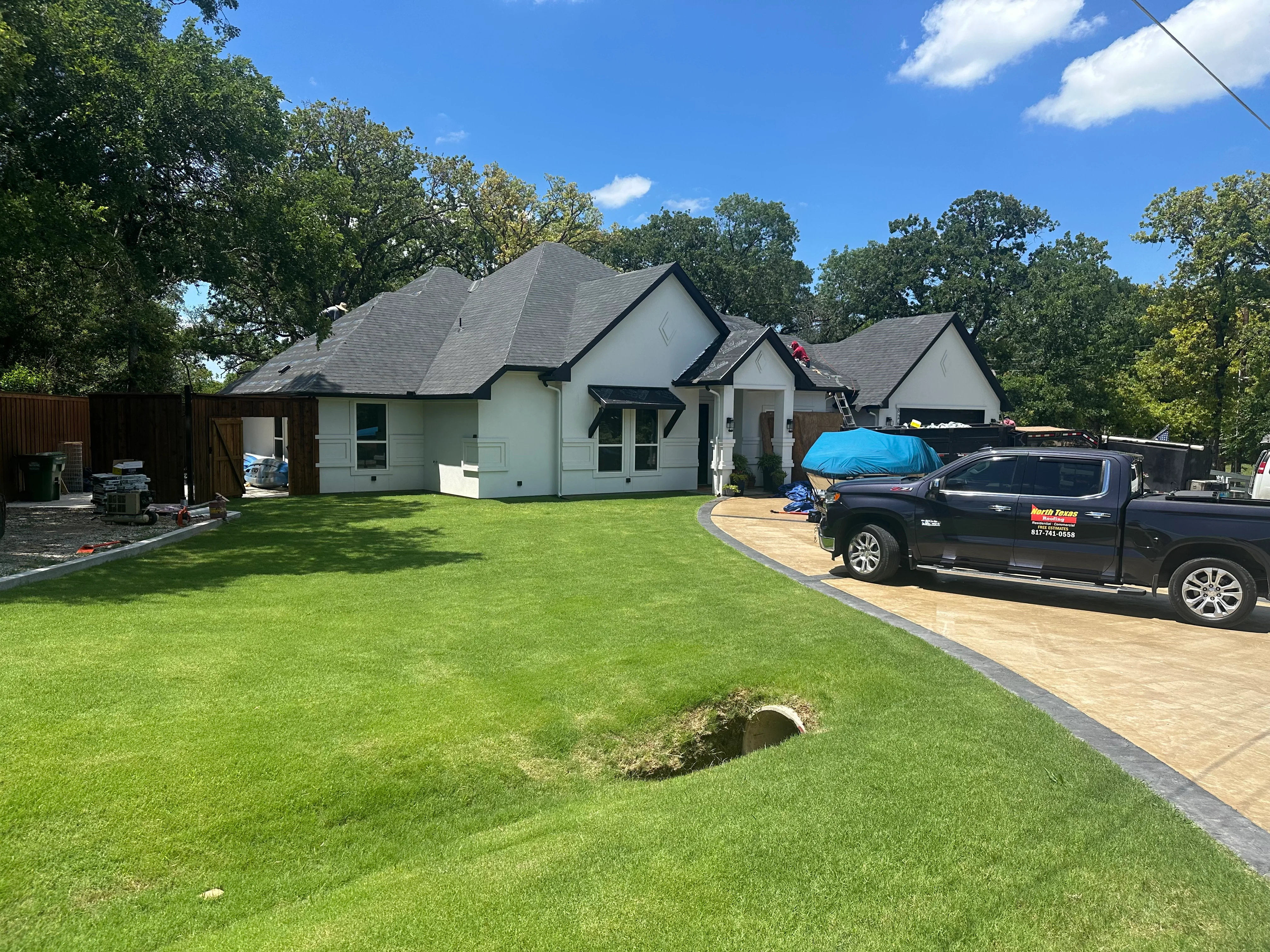 Dark gray architectural shingle roof installation on white residential home with multiple peaks and gables