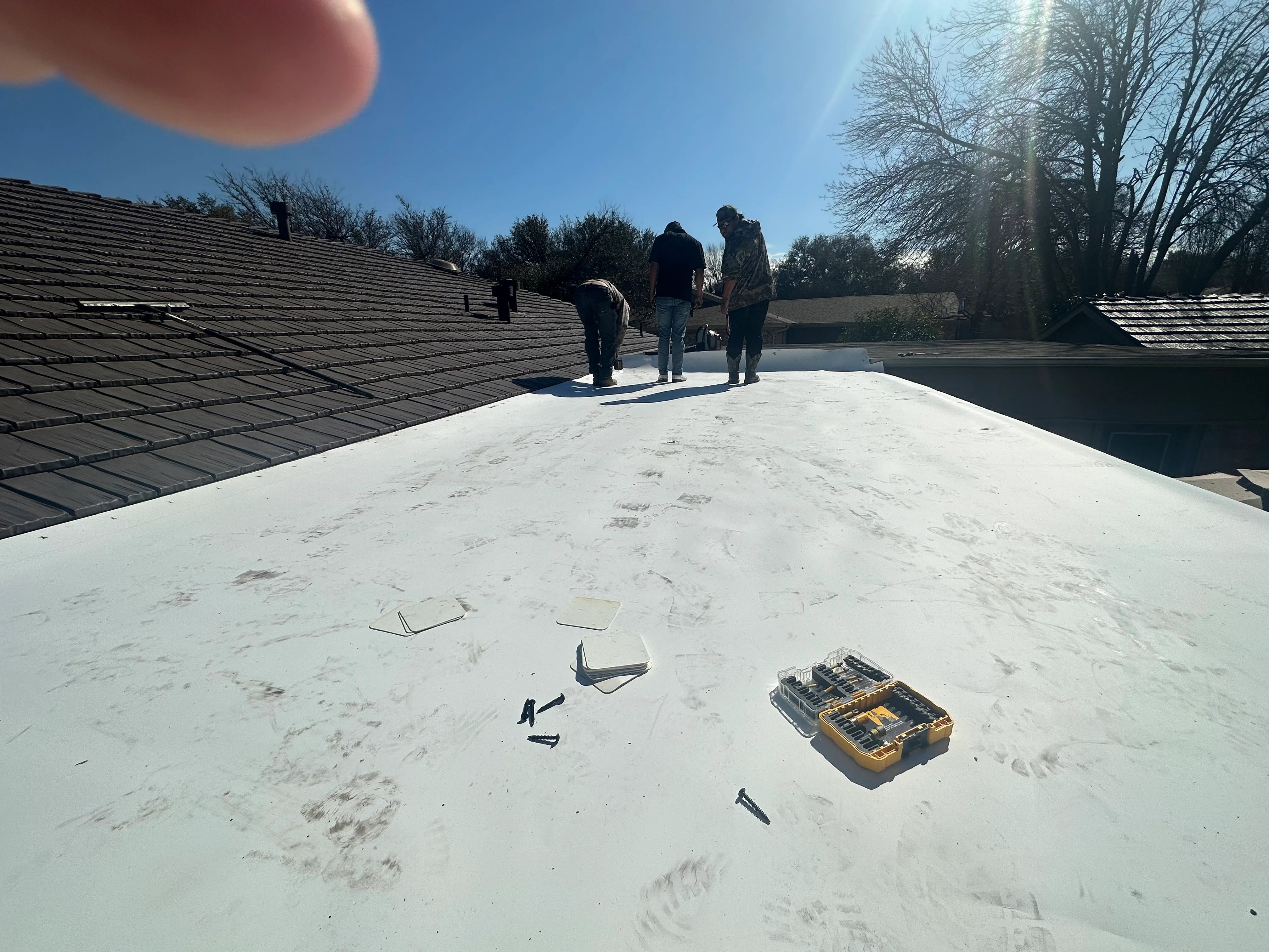Flat roof membrane inspection with tools and crew assessing surface condition
