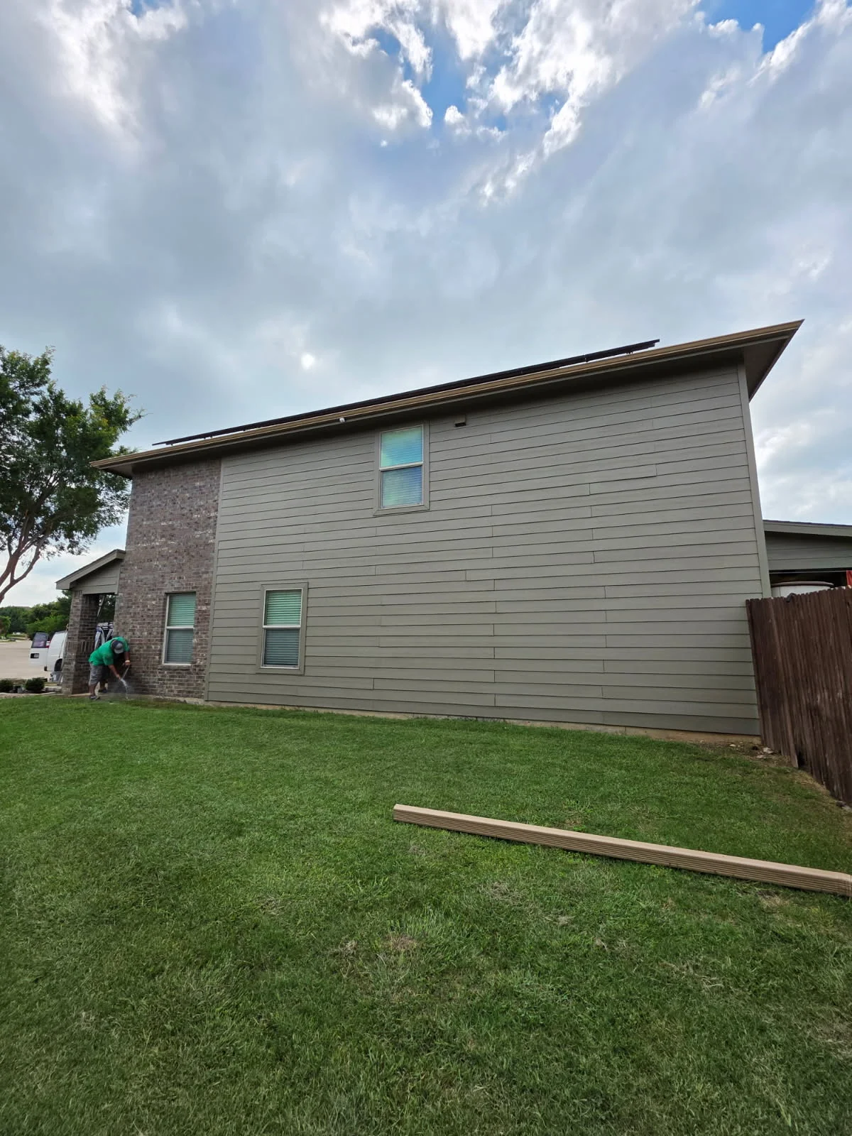 New pitched metal roof with dark trim installed on two-story residential home with brick and siding exterior